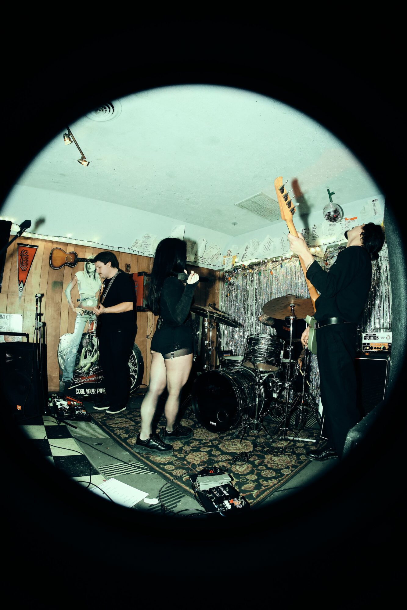 People performing music and singing in a room with musical instruments and a patterned rug.