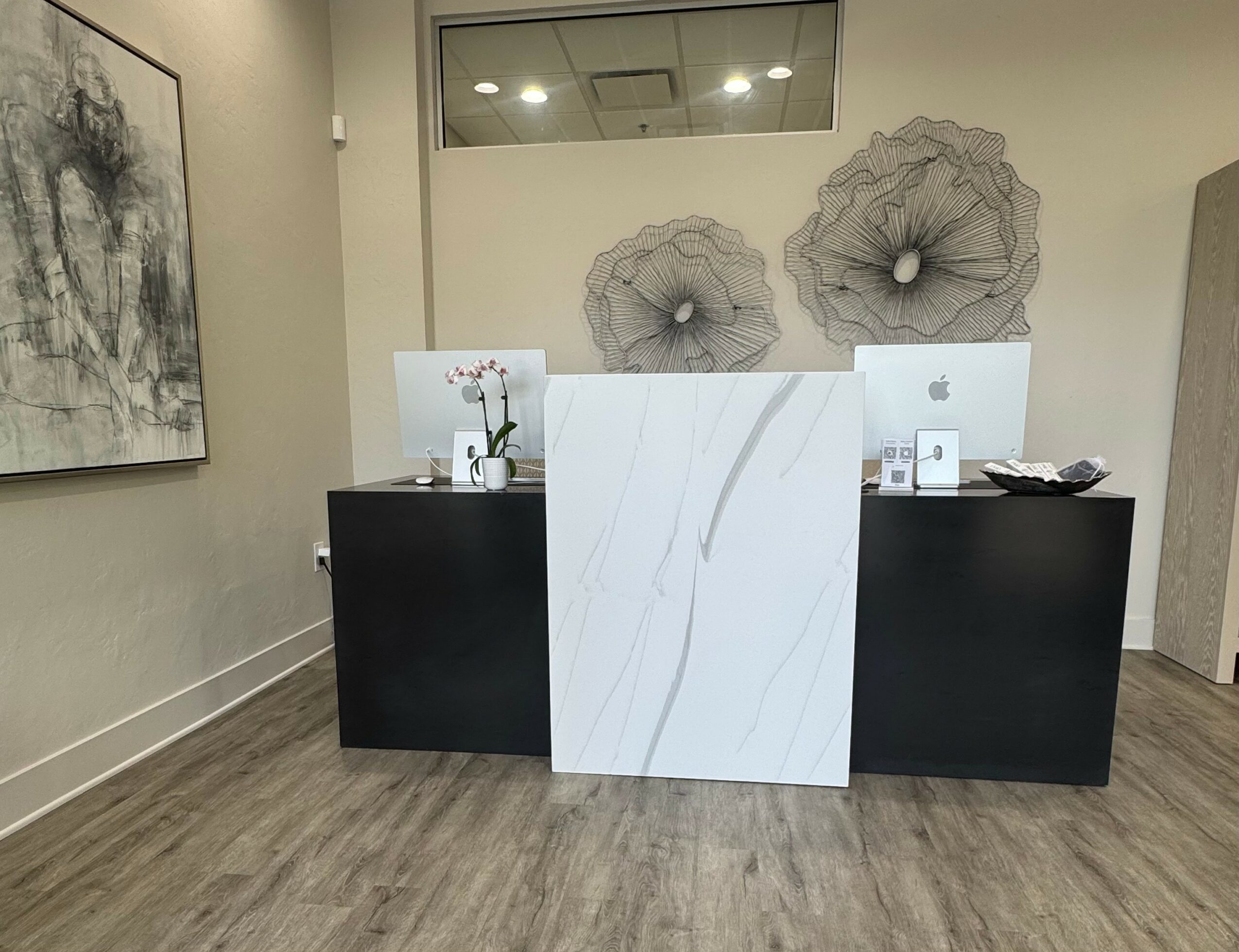 Reception desk with white and black panels, wall art, and decorative umbrellas, in a modern interior.