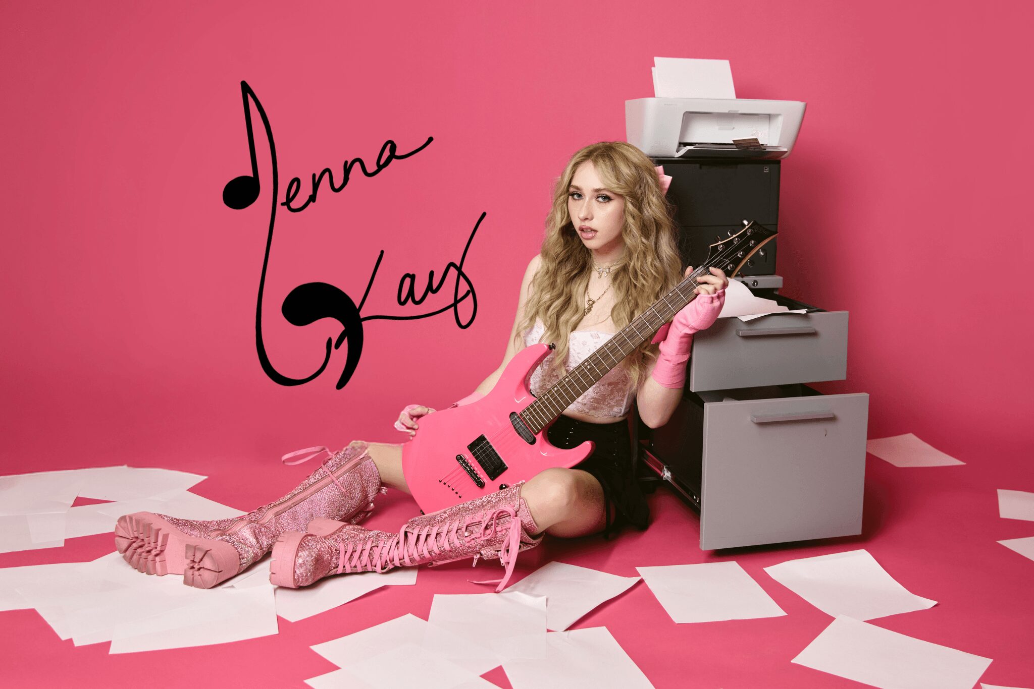 Young woman with long blonde hair sitting on pink floor, holding a pink guitar, surrounded by papers, pink background, signature reads Jenna Kay.
