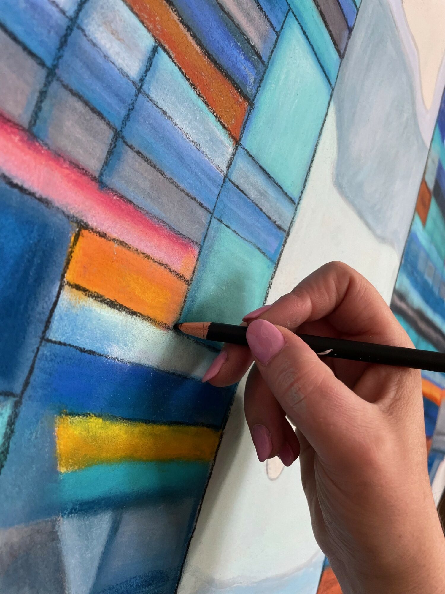 Person holding a pencil, working on a colorful abstract painting with geometric shapes.