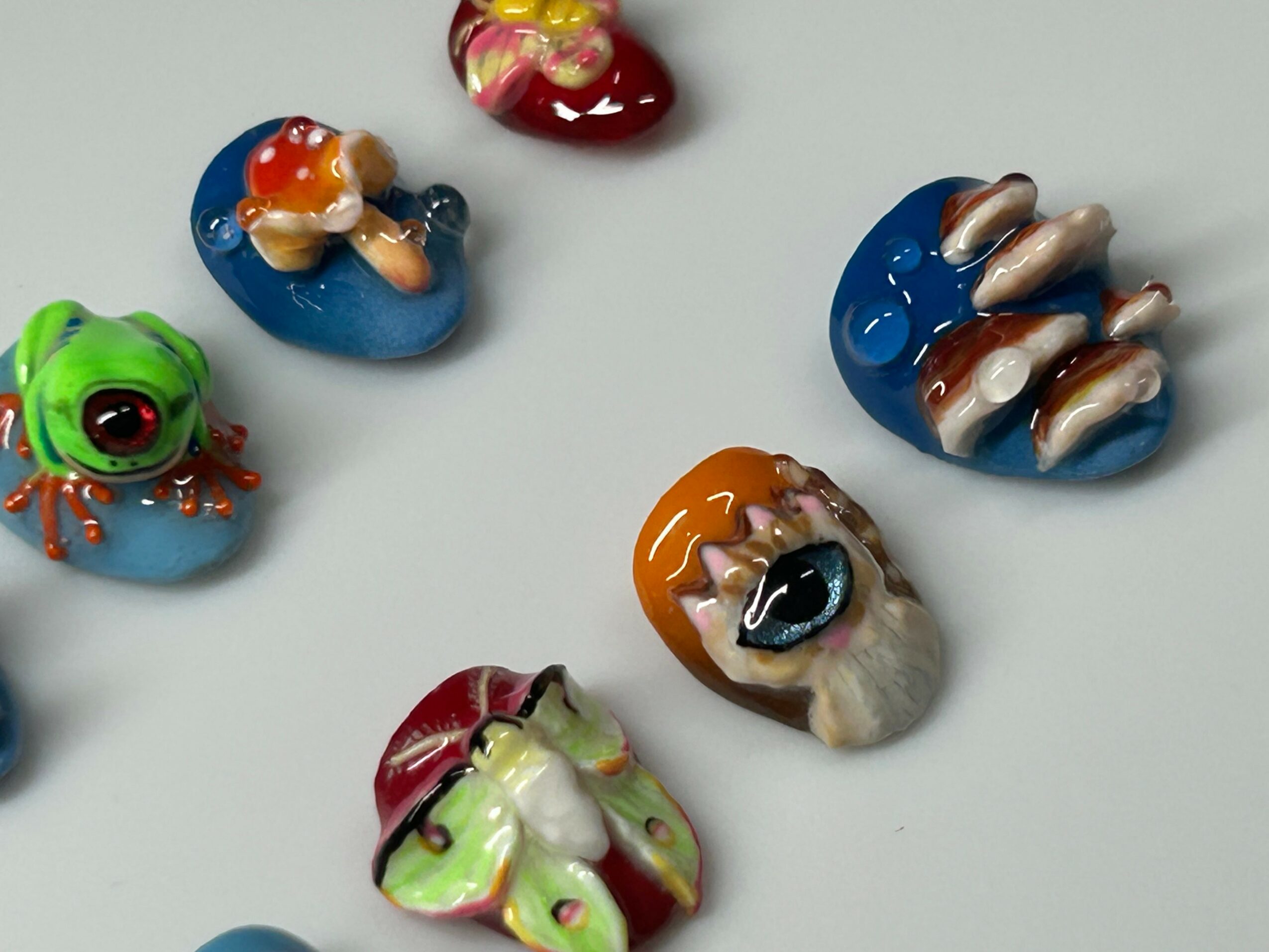 Colorful small toys resembling animals and creatures on a white surface.