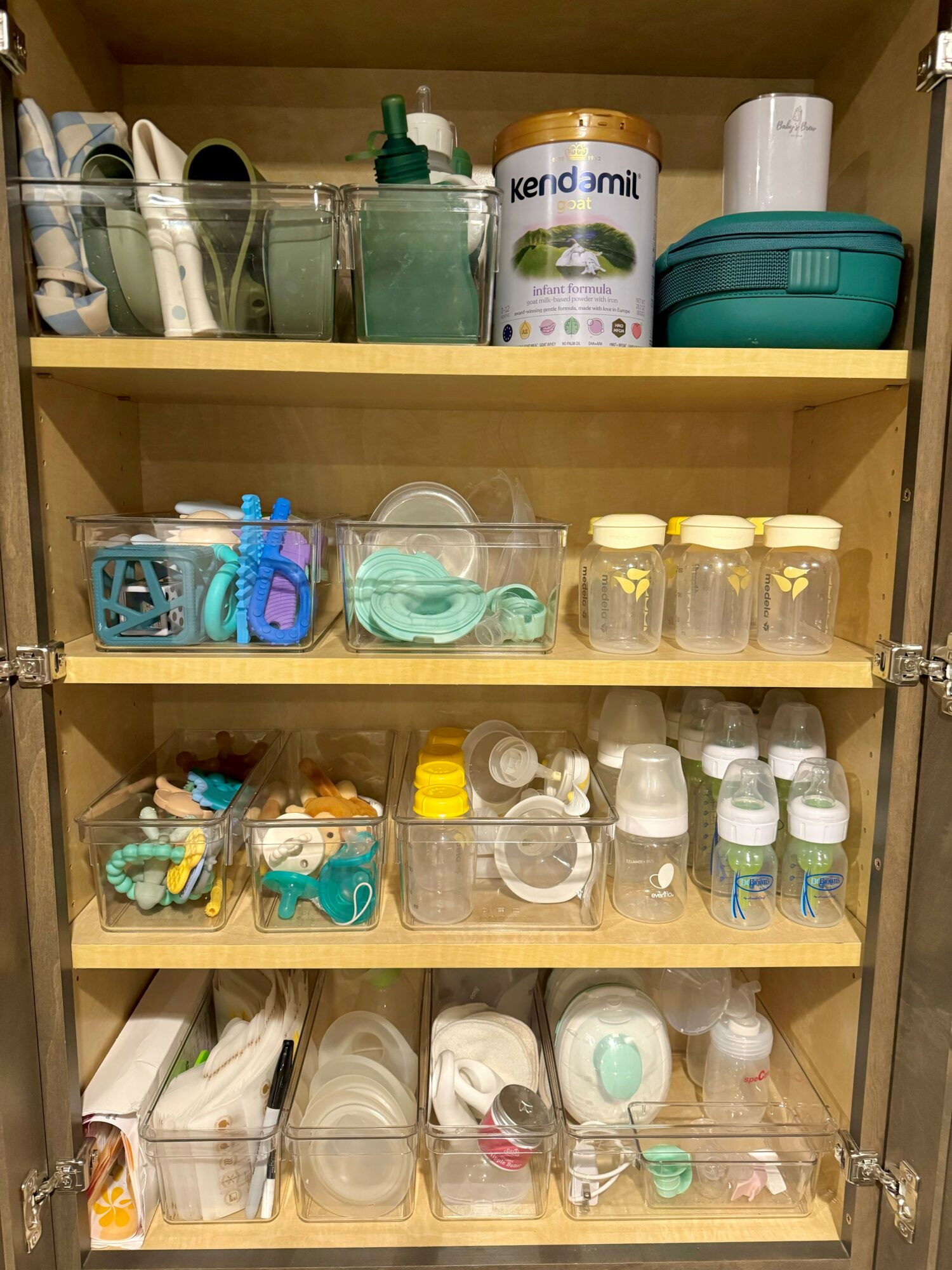 Shelves with baby bottles, pacifiers, and baby care items organized in containers.