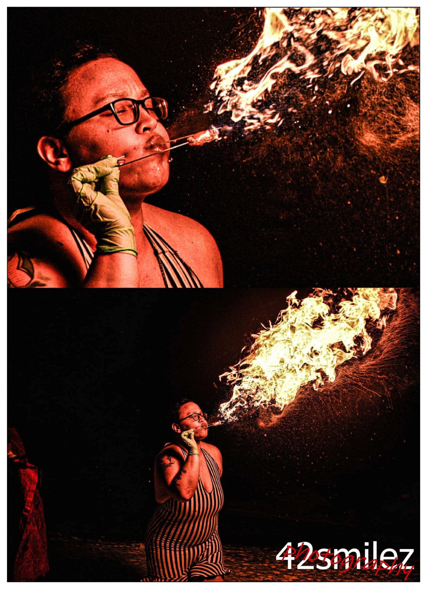 Two women perform fire breathing, creating large flames, one in a striped dress and glasses, the other in a striped top, at night.