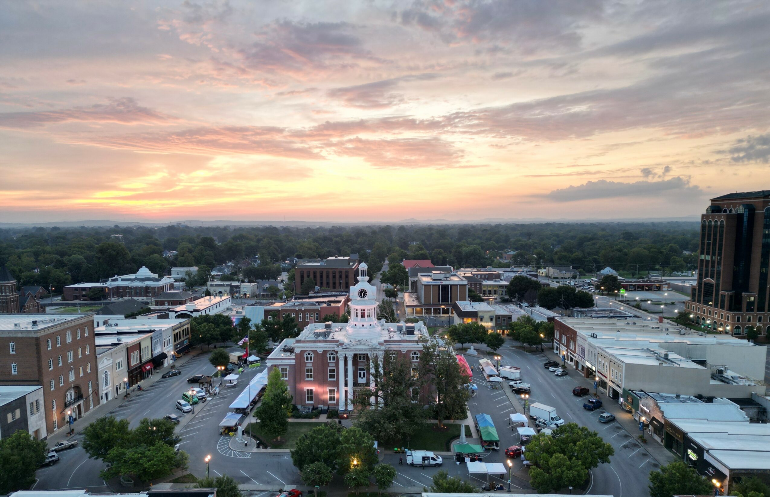 Cityscape with a sunset sky, buildings, and a parking lot in foreground.