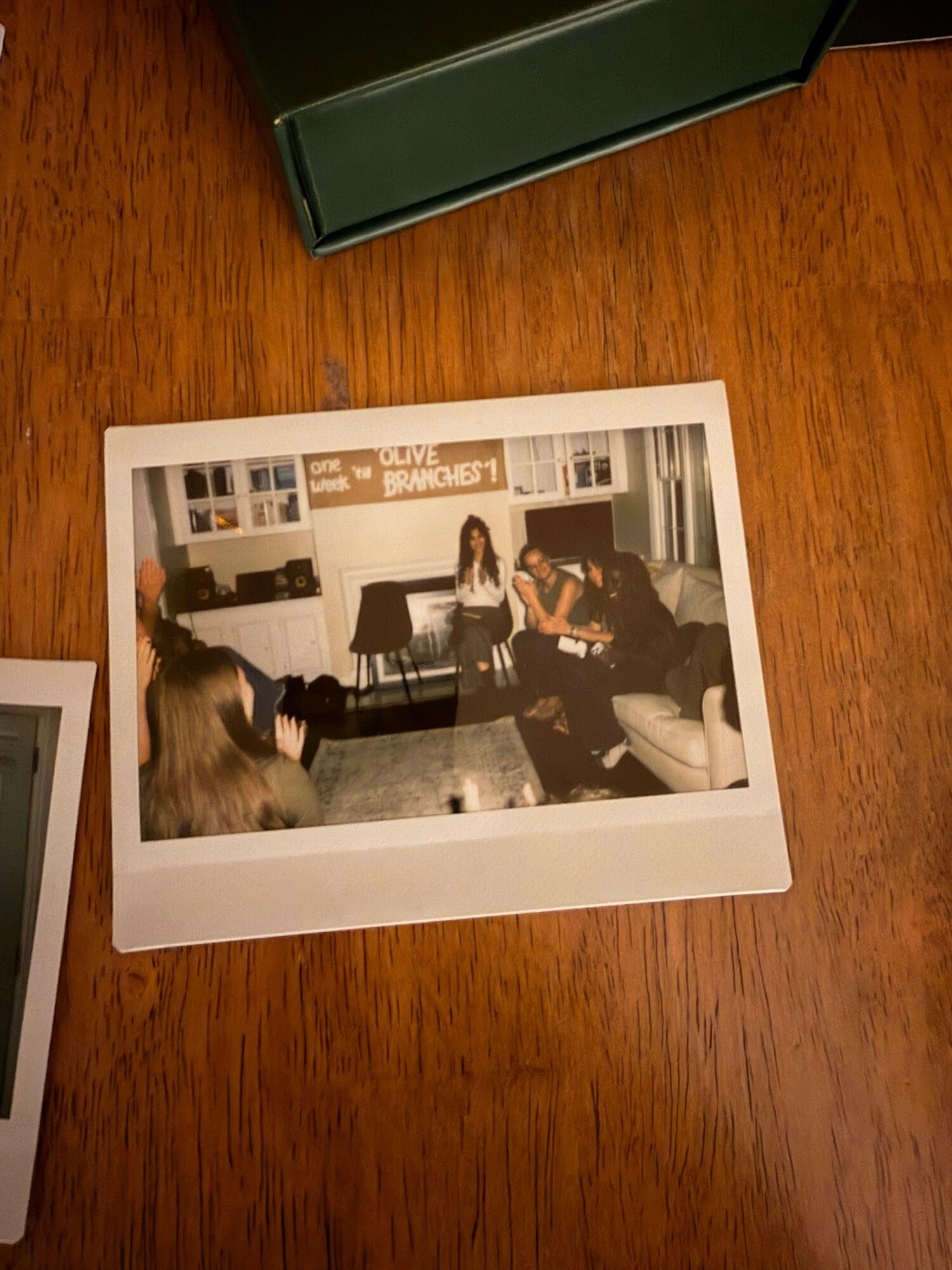 Photograph of two people sitting and talking in a room with bookshelves, a window, and a carpeted floor.