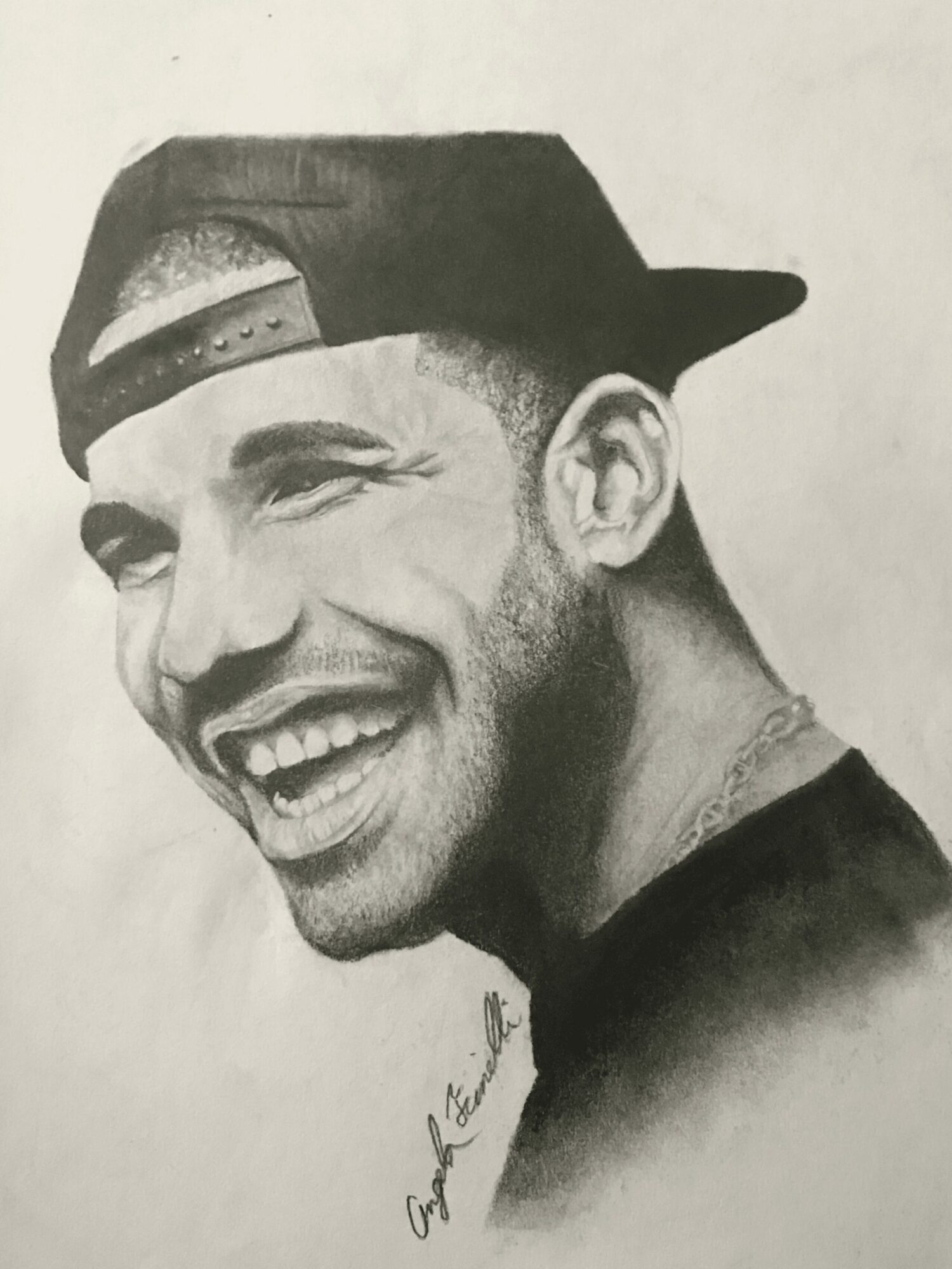 Black and white portrait of a smiling young man wearing a backward cap, showing teeth and facial hair.