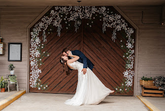 A couple in wedding attire dancing in front of a decorated wooden door with floral arrangements.