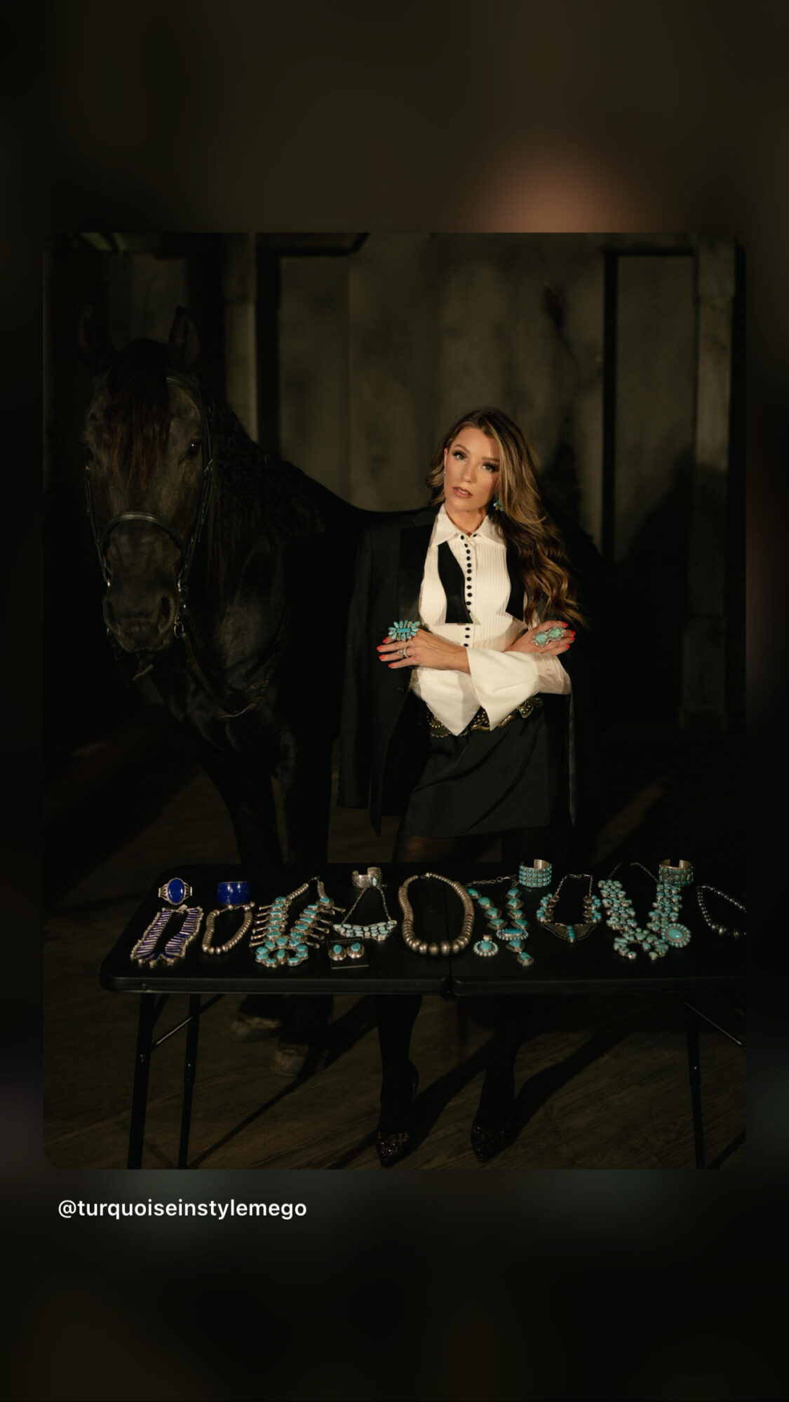 Woman in black and white outfit standing next to a horse, with decorative text on a table in front.