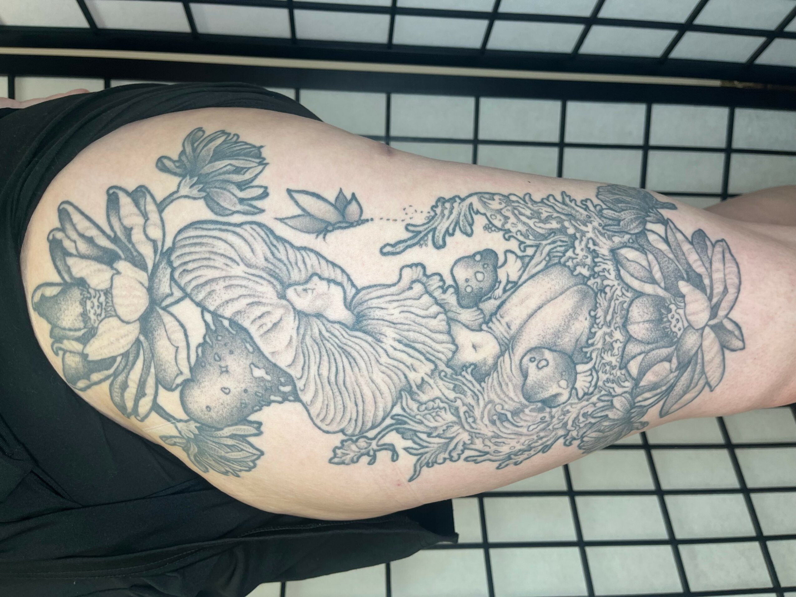 Tattoo of flowers, a lion, and a bear on a person's arm, with detailed line work and shading.