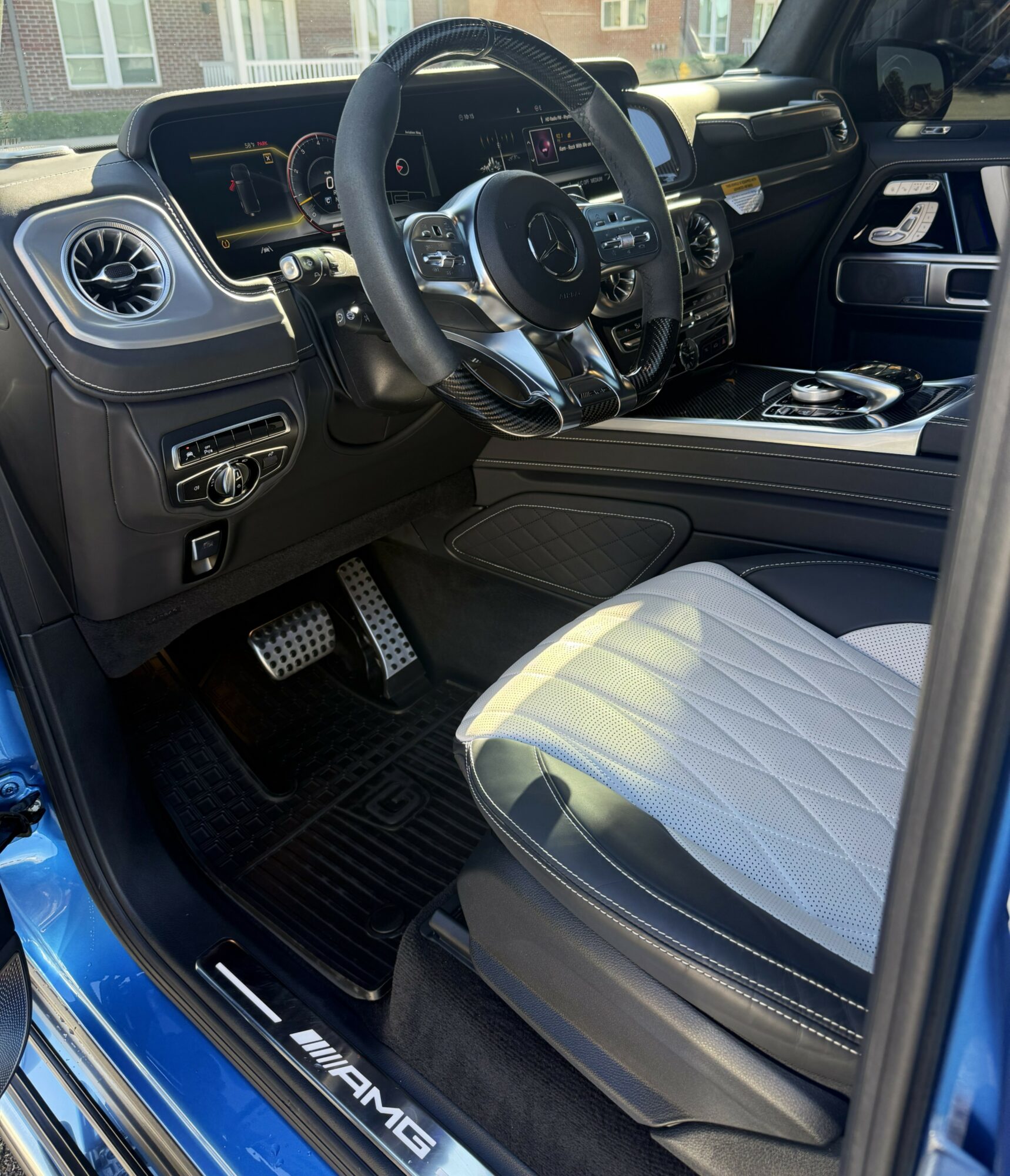 Car interior showing steering wheel, dashboard, gear shift, and front seat with quilted upholstery.