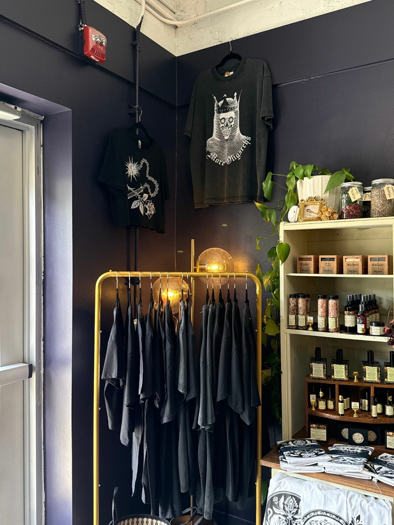 Interior of a clothing store with black walls, clothing racks, and shelves with products, illuminated by warm lighting.