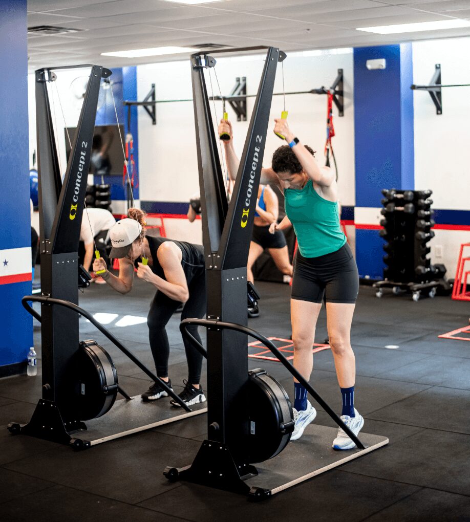 People exercising with resistance bands in a gym, with equipment and mirrors in the background.