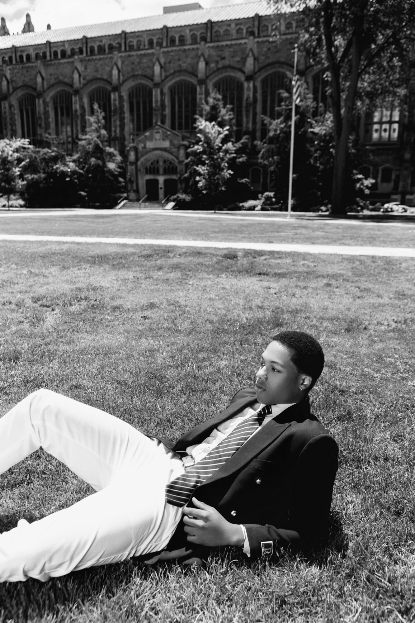Person lying on grass in a park with a historic building in the background.