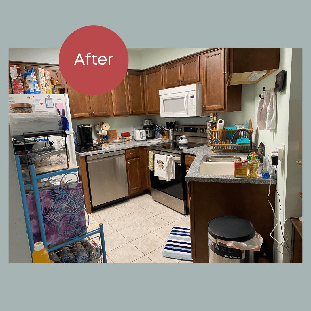 Clean kitchen with wooden cabinets, microwave, and organized countertop. Refrigerator, trash can, and a striped rug are visible.