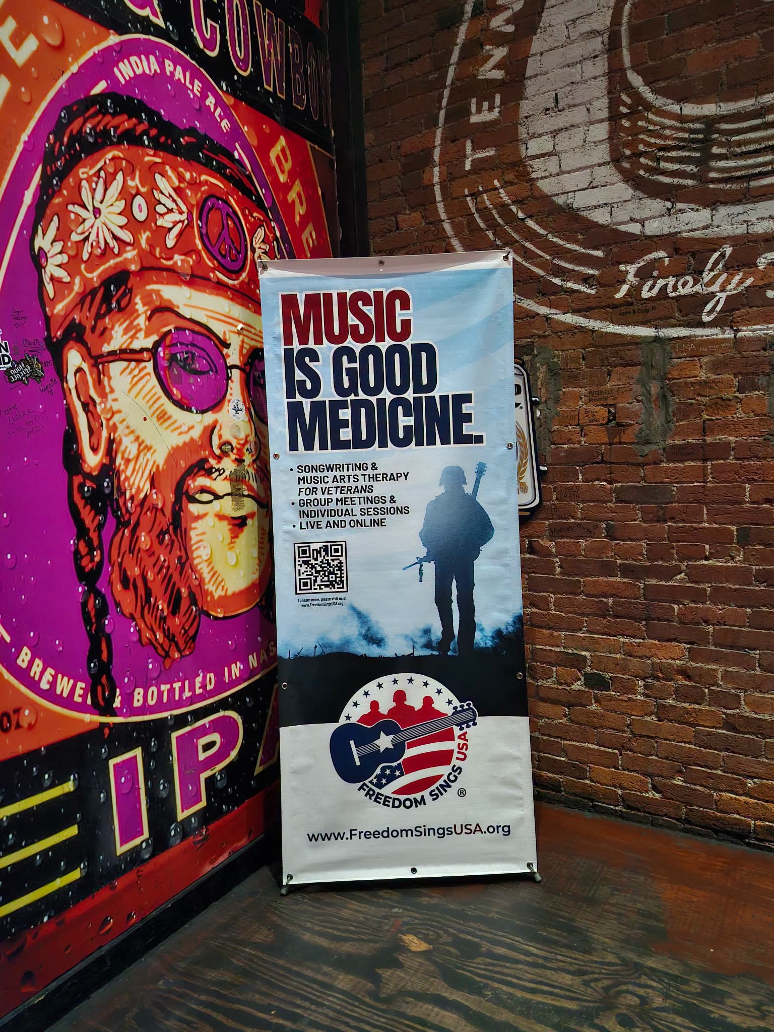 Poster with the message 'Music is good medicine' and a silhouette of a person with a guitar, against a brick wall.