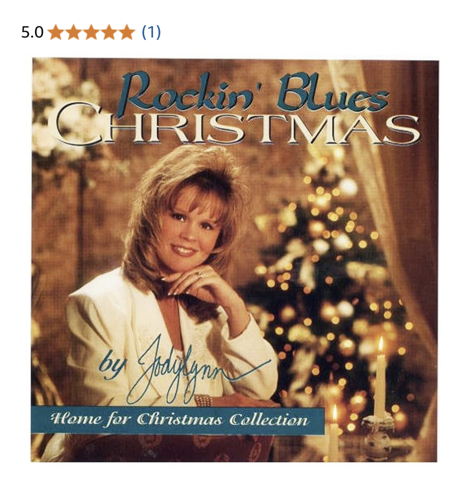 Young girl with blonde hair smiling, Christmas tree with lights in background, album cover for Christmas music collection.