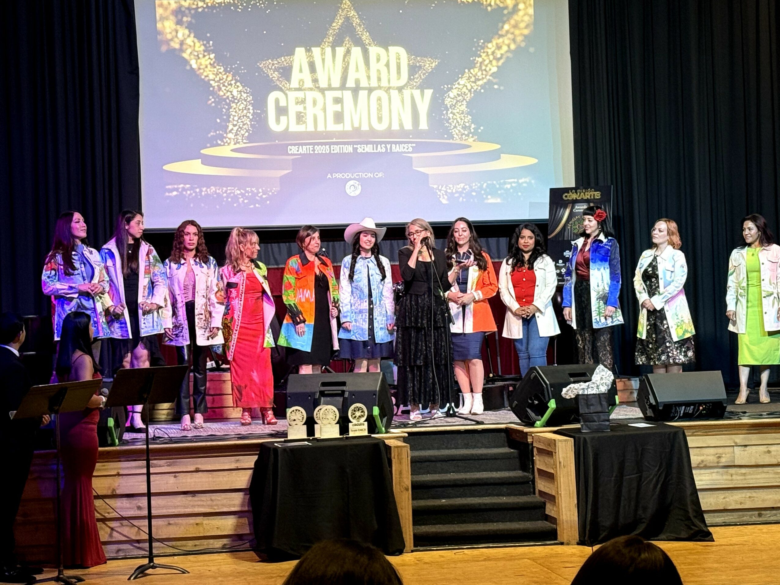Group of people on stage at an award ceremony, with a large screen behind displaying 'AWARD CEREMONY'.