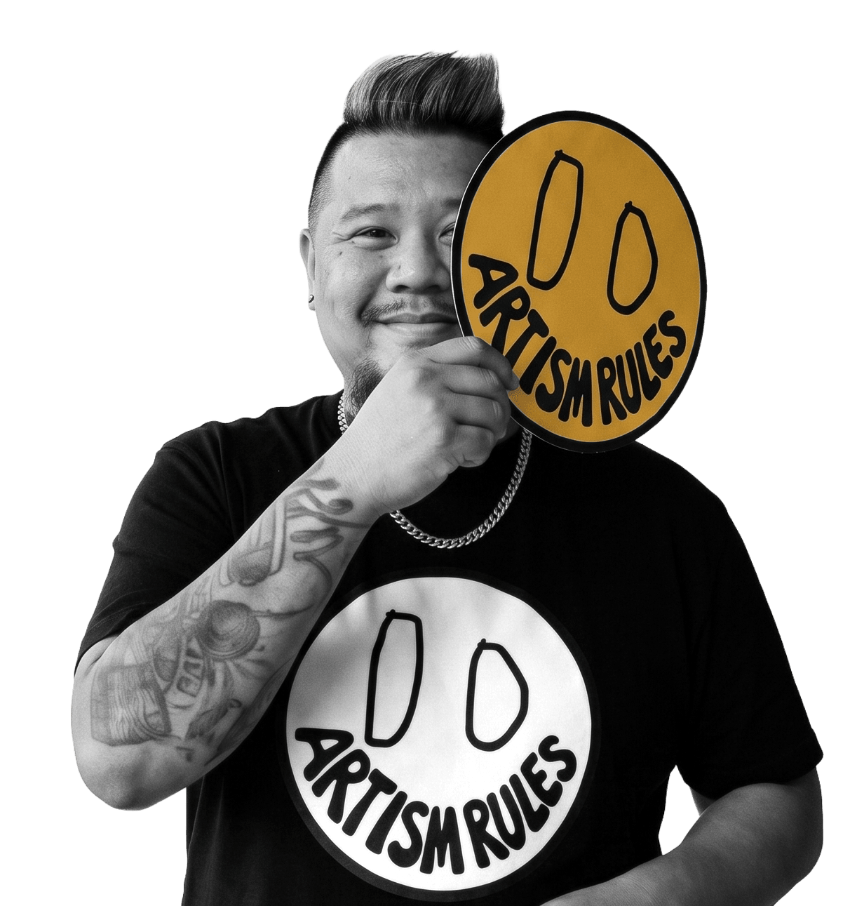 Person holding a sign with a smiley face and the text 'ARTISM RULES', smiling, with tattoos visible on arm.