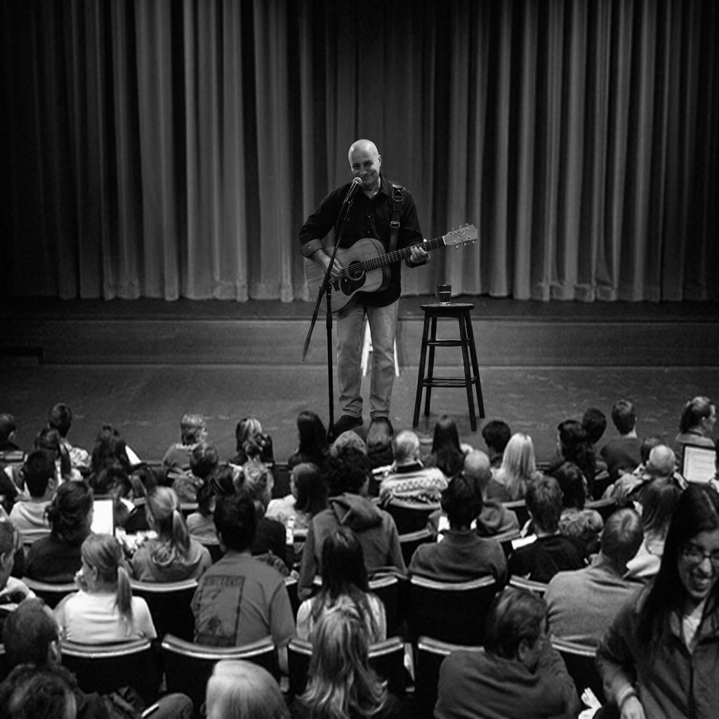 Man performs on stage with guitar in front of audience, curtain backdrop, black and white photo.