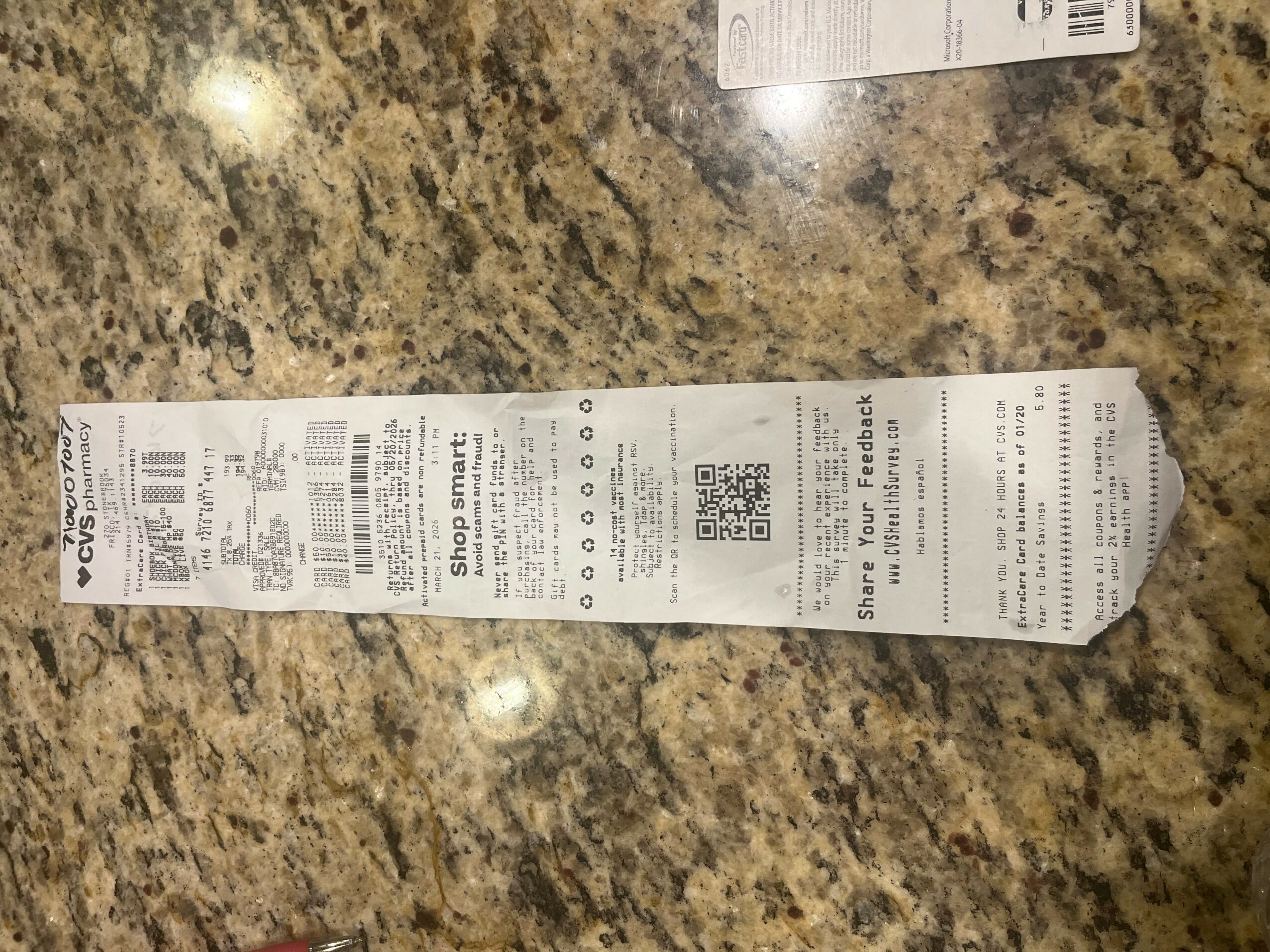 A long, narrow receipt on a granite countertop with printed text and a QR code.