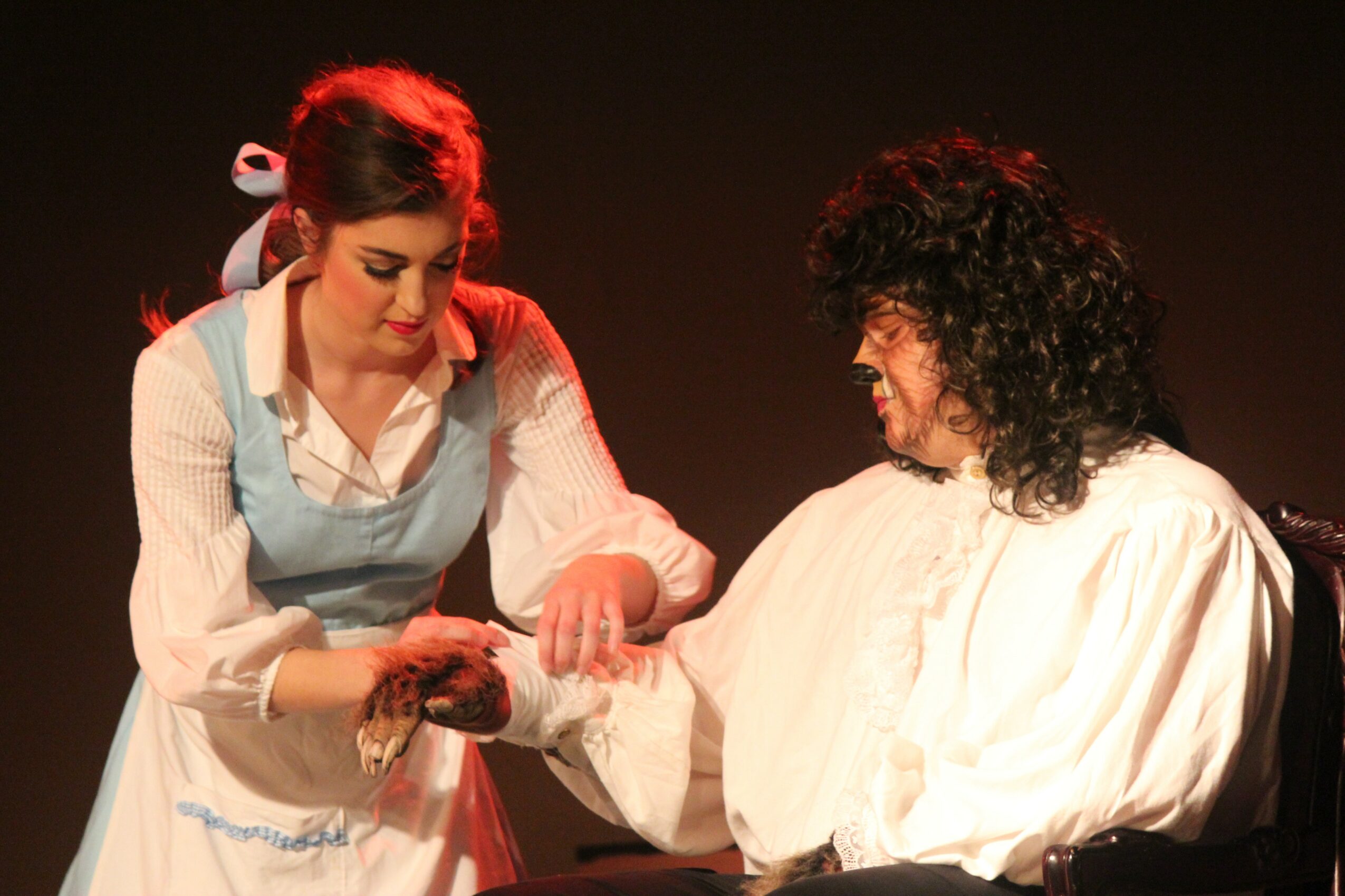 Two women, one with dark curly hair and the other with light brown hair, are engaged in a handshake or exchange on stage.