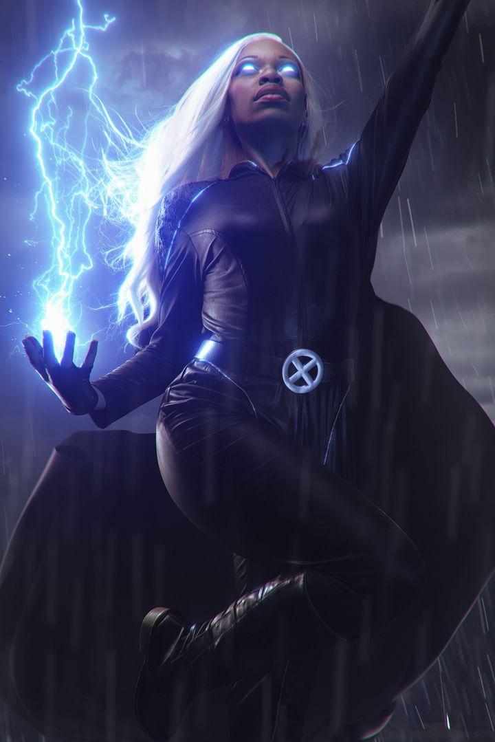 Woman with white hair in a black costume, holding lightning, in a rainstorm, with a dark background.