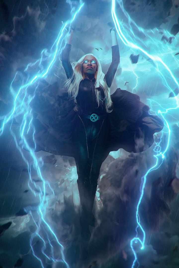 A woman with long blonde hair stands with arms raised amid lightning and stormy clouds, wearing dark clothing and a necklace.