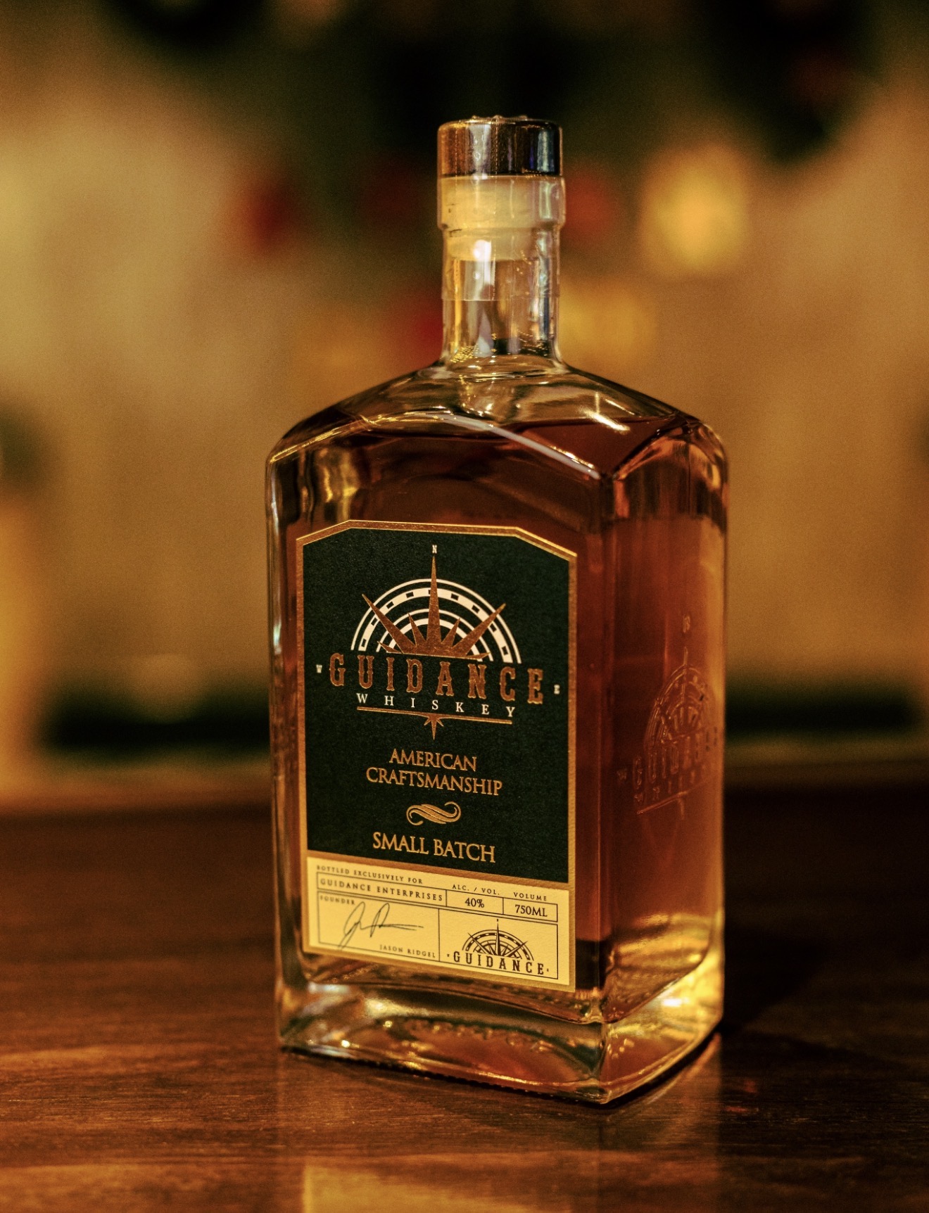 Bottle of whiskey with a green label on a wooden surface, blurred background, upright position.