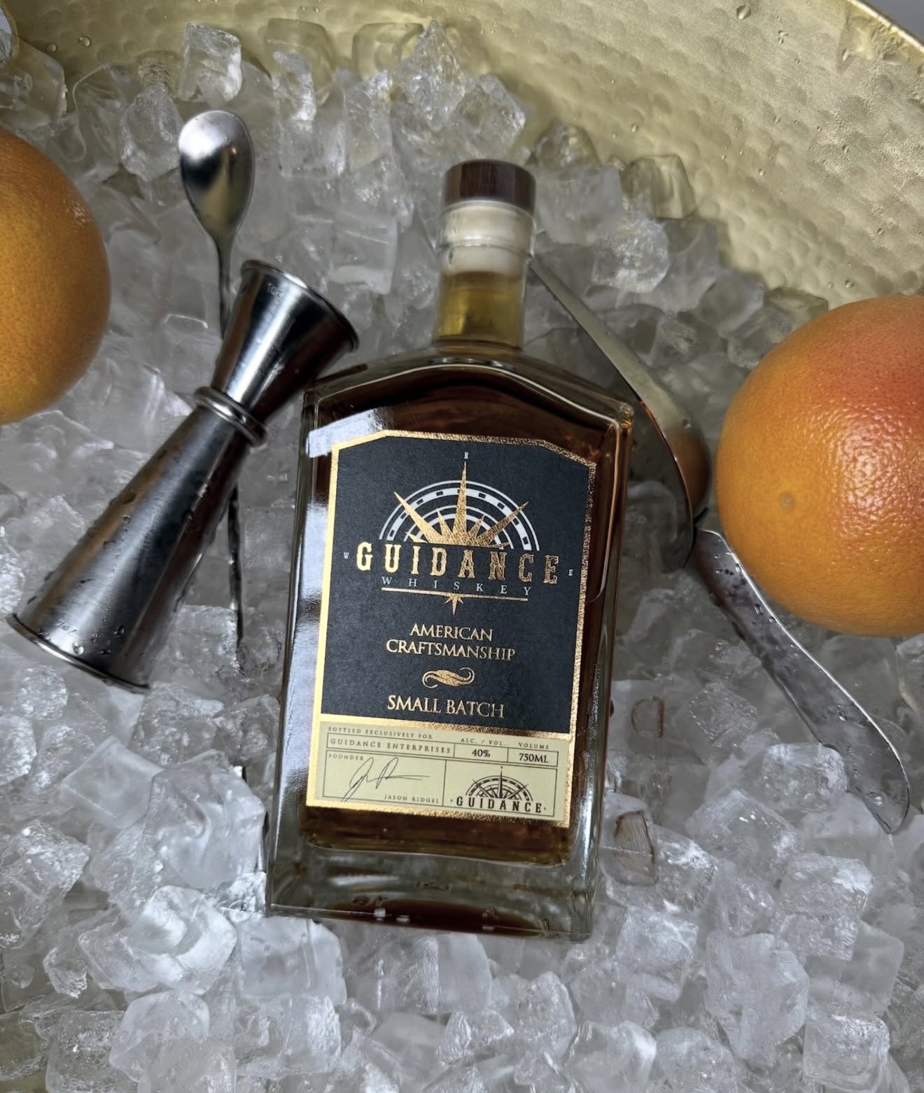 Bottle of Guidance American craftsmanship small batch whiskey on ice with oranges nearby.