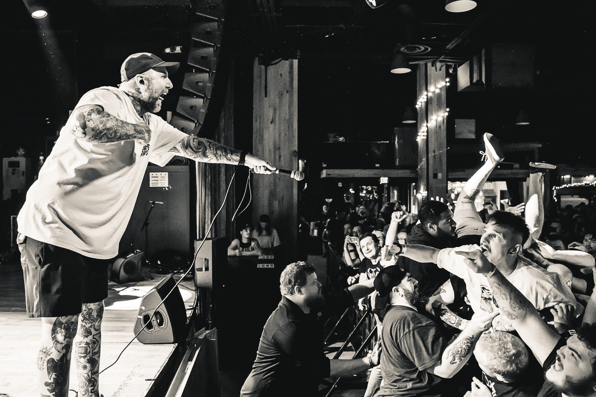 Performer on stage pointing at audience, crowd reaching out with hands, black and white photo, lively atmosphere