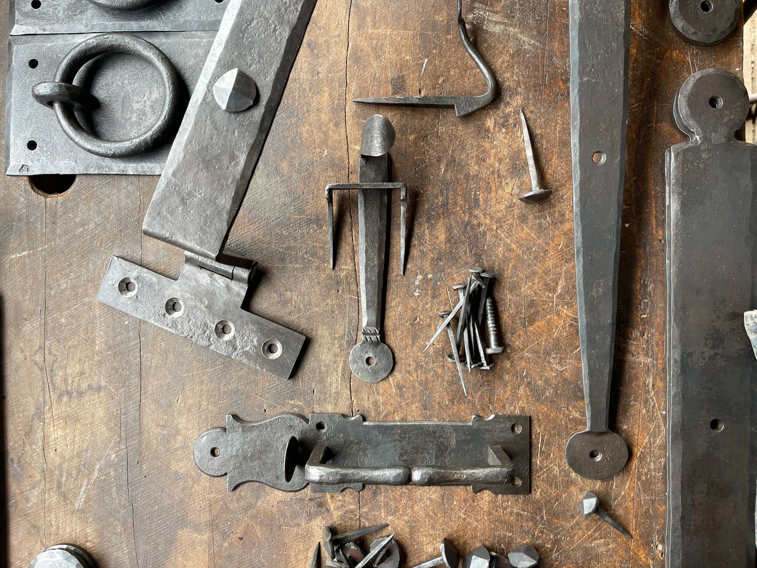 Various metal tools and parts arranged on a wooden surface, including a wrench, screws, and metal strips.