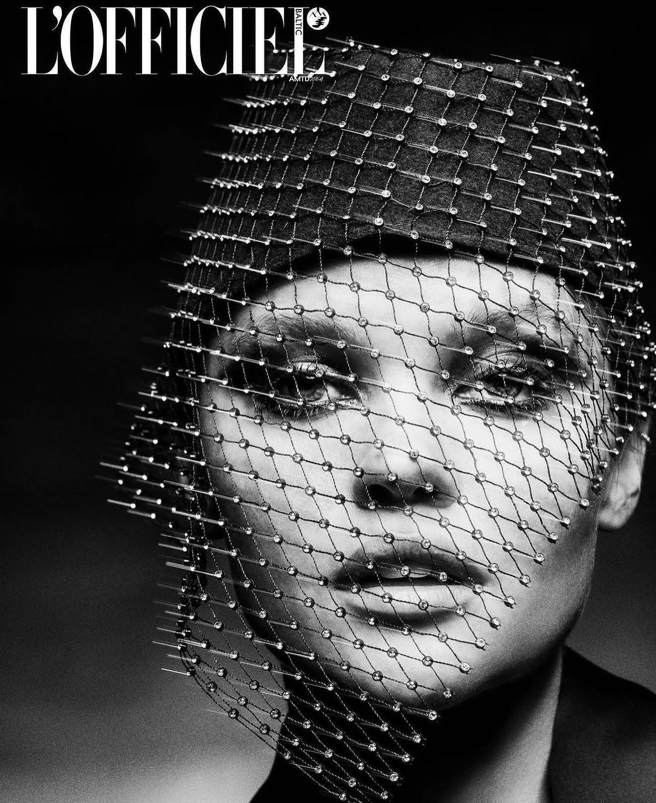 Woman wearing a beaded headpiece with a netted veil, magazine cover style, black and white, high fashion look.