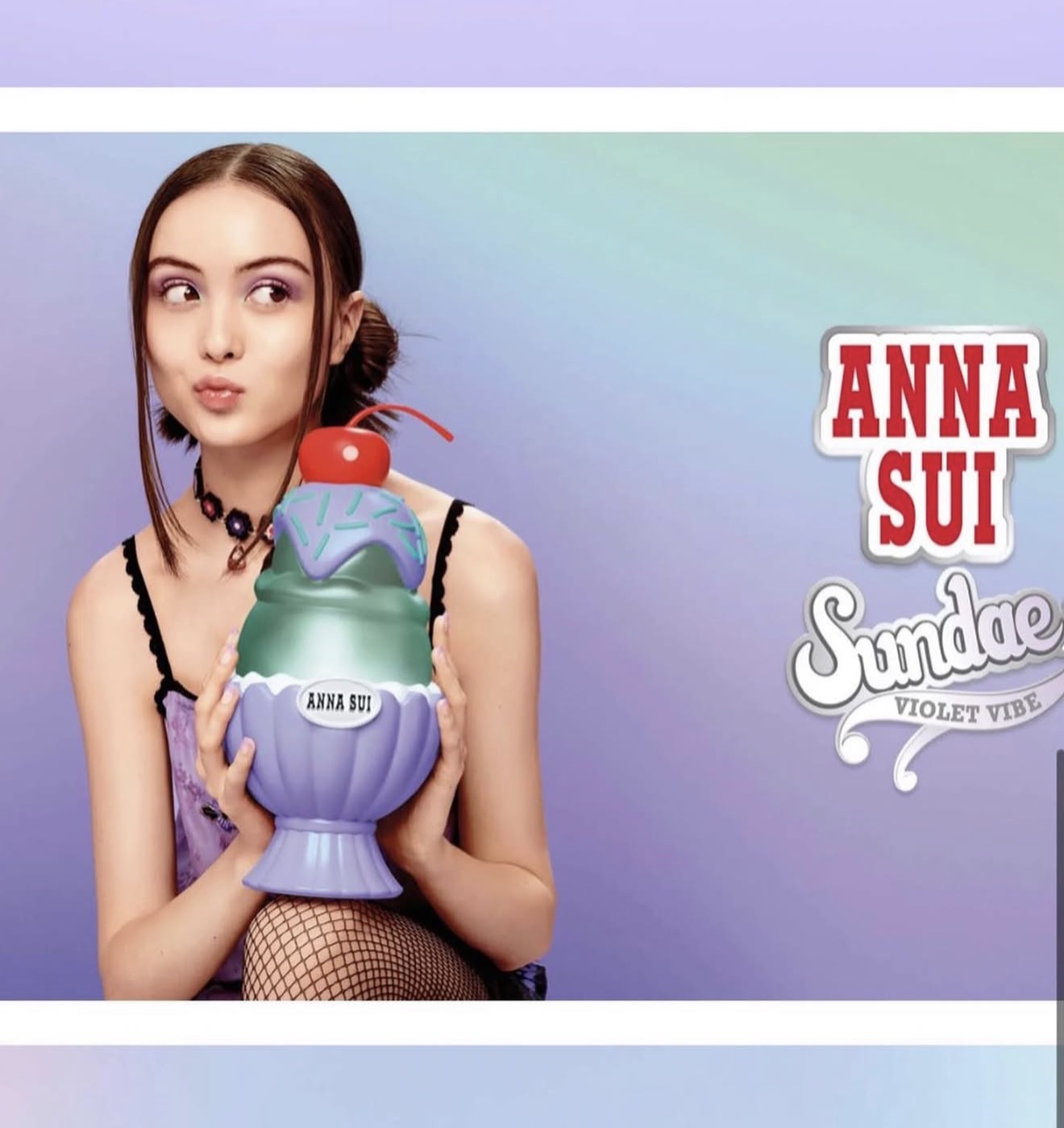Young woman with dark hair holding a colorful toy, wearing a purple top and fishnet stockings, against a pastel background.