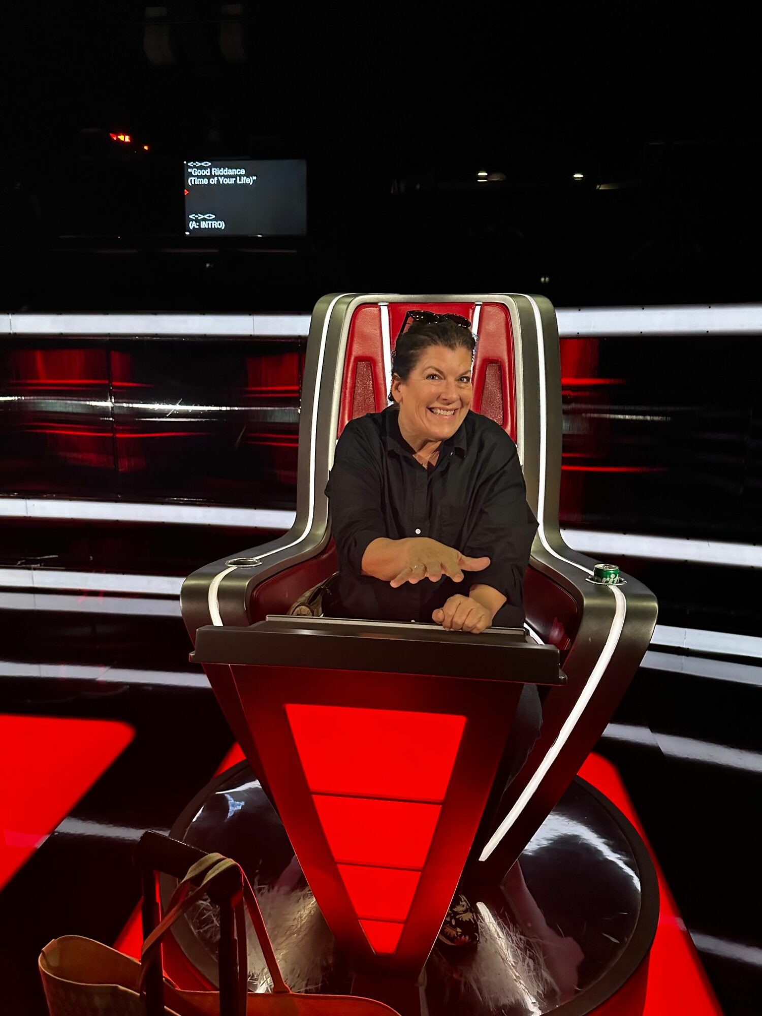 Person sitting in a futuristic red and black chair with a high back, in a dark environment with vertical light strips.