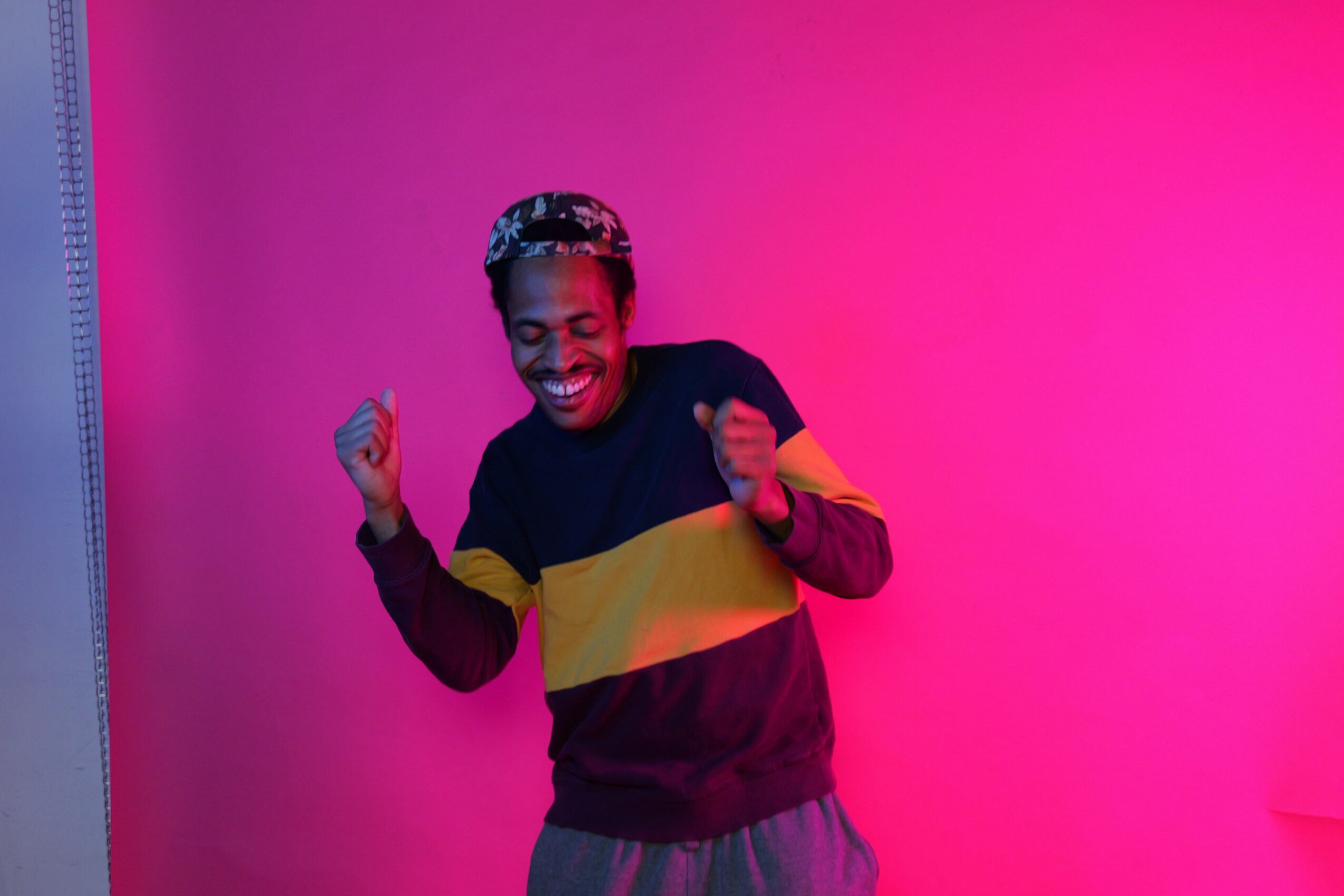 Child smiling and dancing against a pink and purple gradient background.
