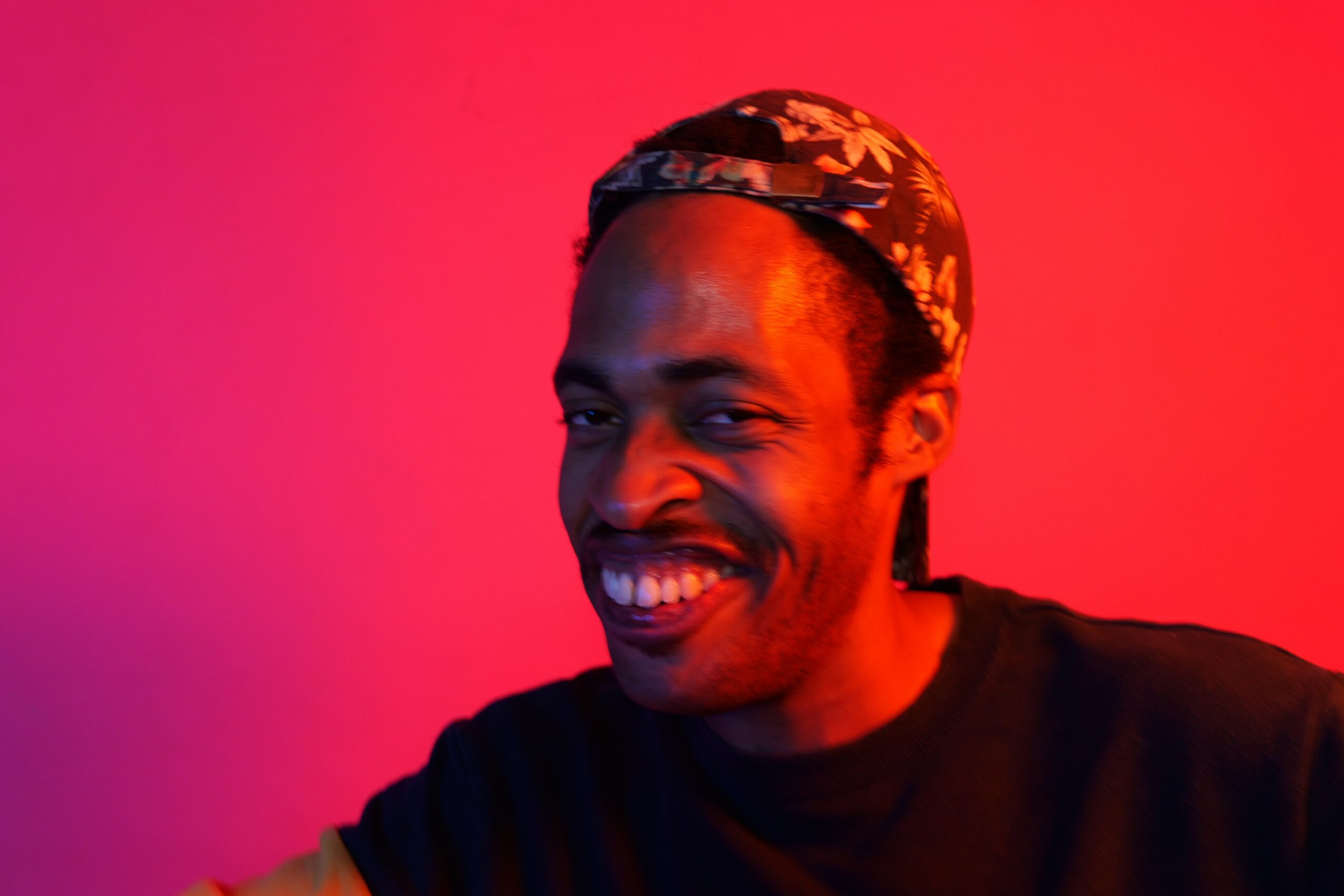 Smiling person wearing a patterned headband against a red background.