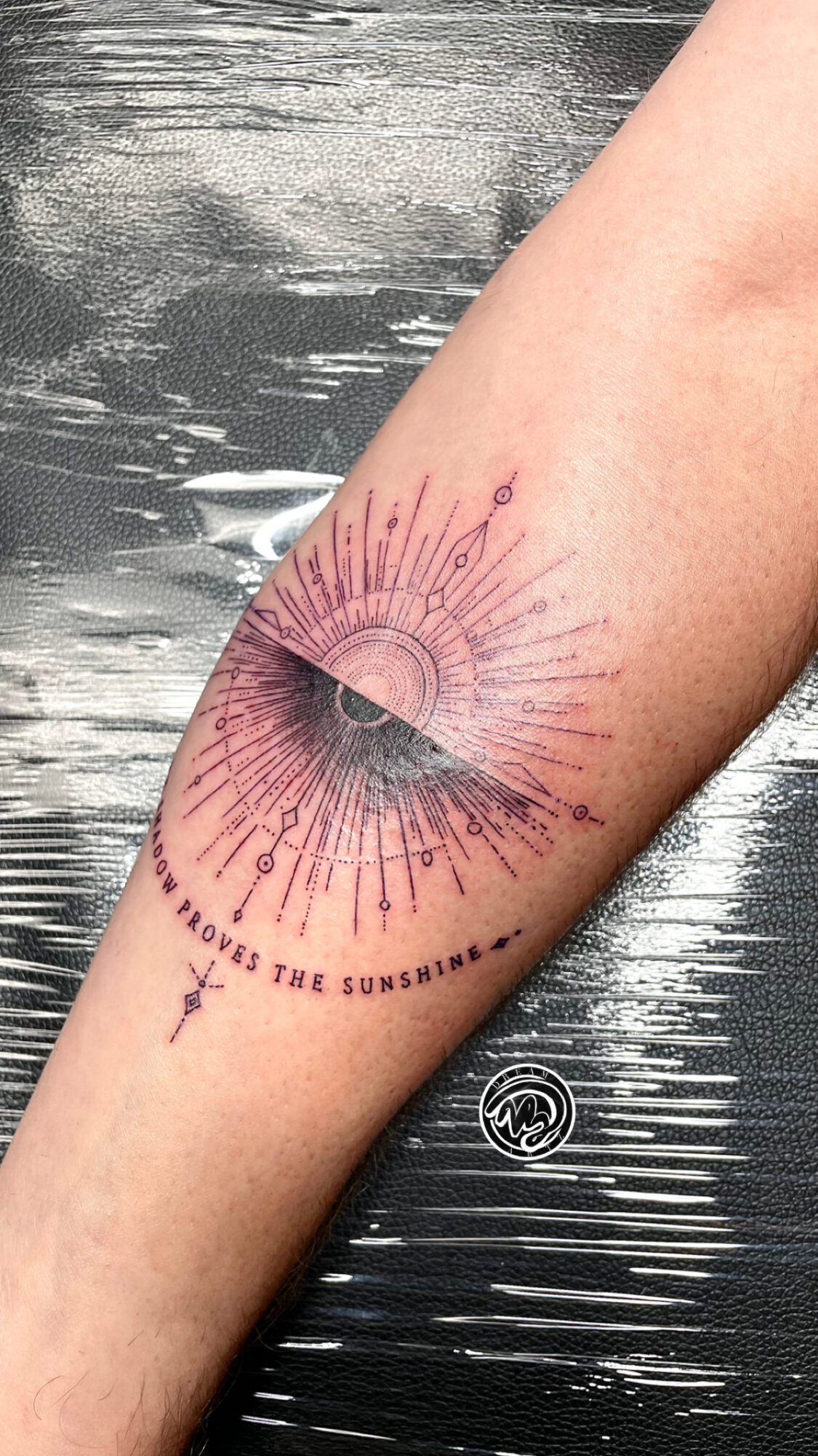 Tattoo of an eye with radiating lines on a person's arm, with text below reading 'LOVE THE SUNSHINE'.