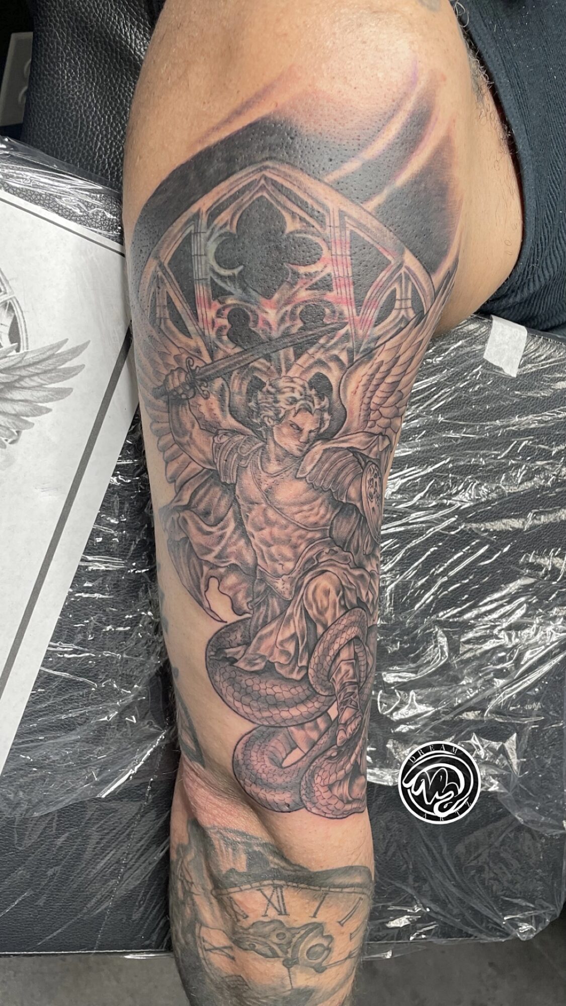 Detailed tattoo of a woman with a snake on the upper arm and shoulder, with intricate patterns and shading.