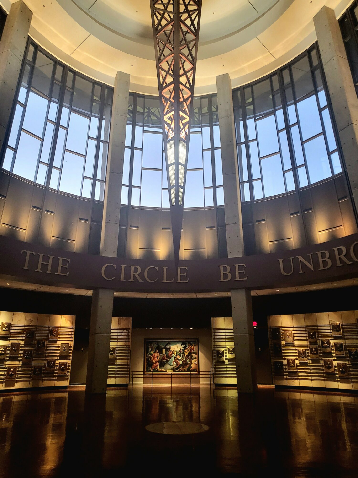 Interior view of a circular building with large windows, a central structure, and a sign reading 'THE CIRCLE BE UNBRO'.