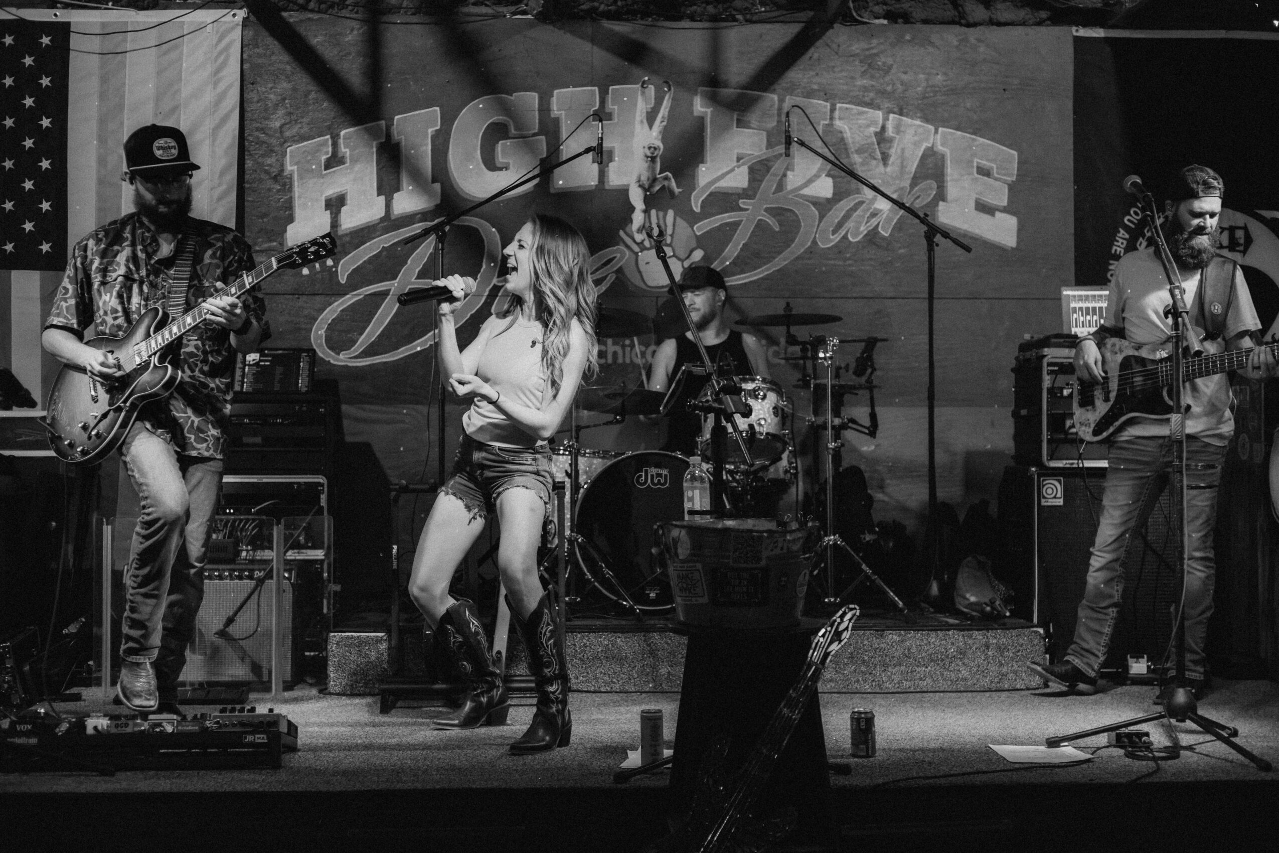 Band performing on stage with four musicians, one singing, with a backdrop reading 'HIGHLINE'.