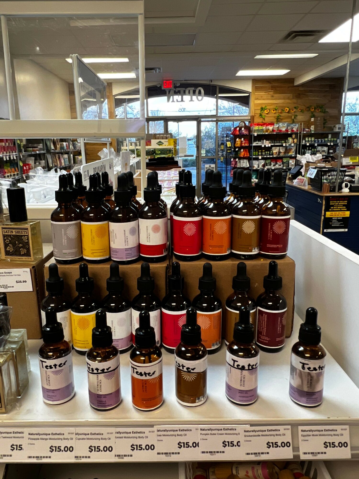 Display of various bottles with colorful labels arranged on a white shelf in a store.