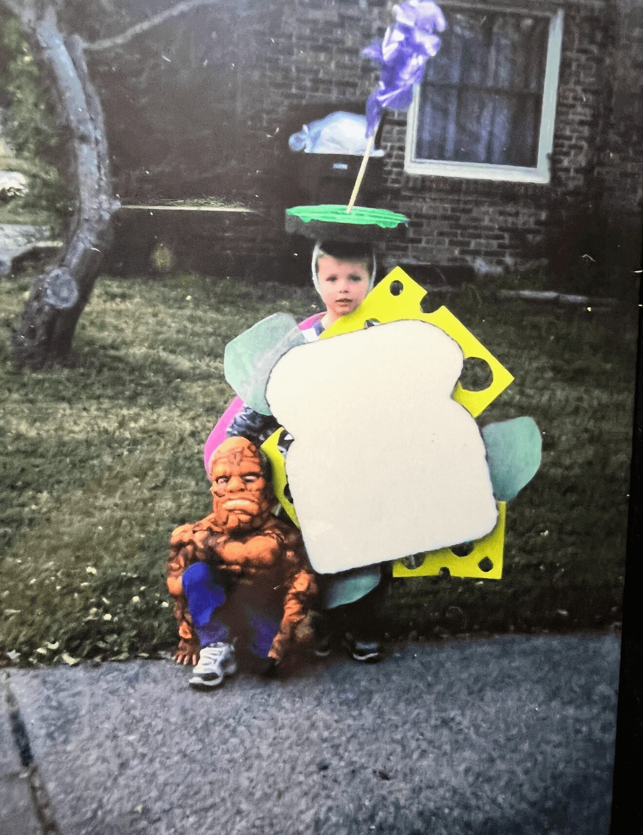 Child dressed as a character with a large white and yellow foam prop, standing outdoors with a small figure in costume nearby.