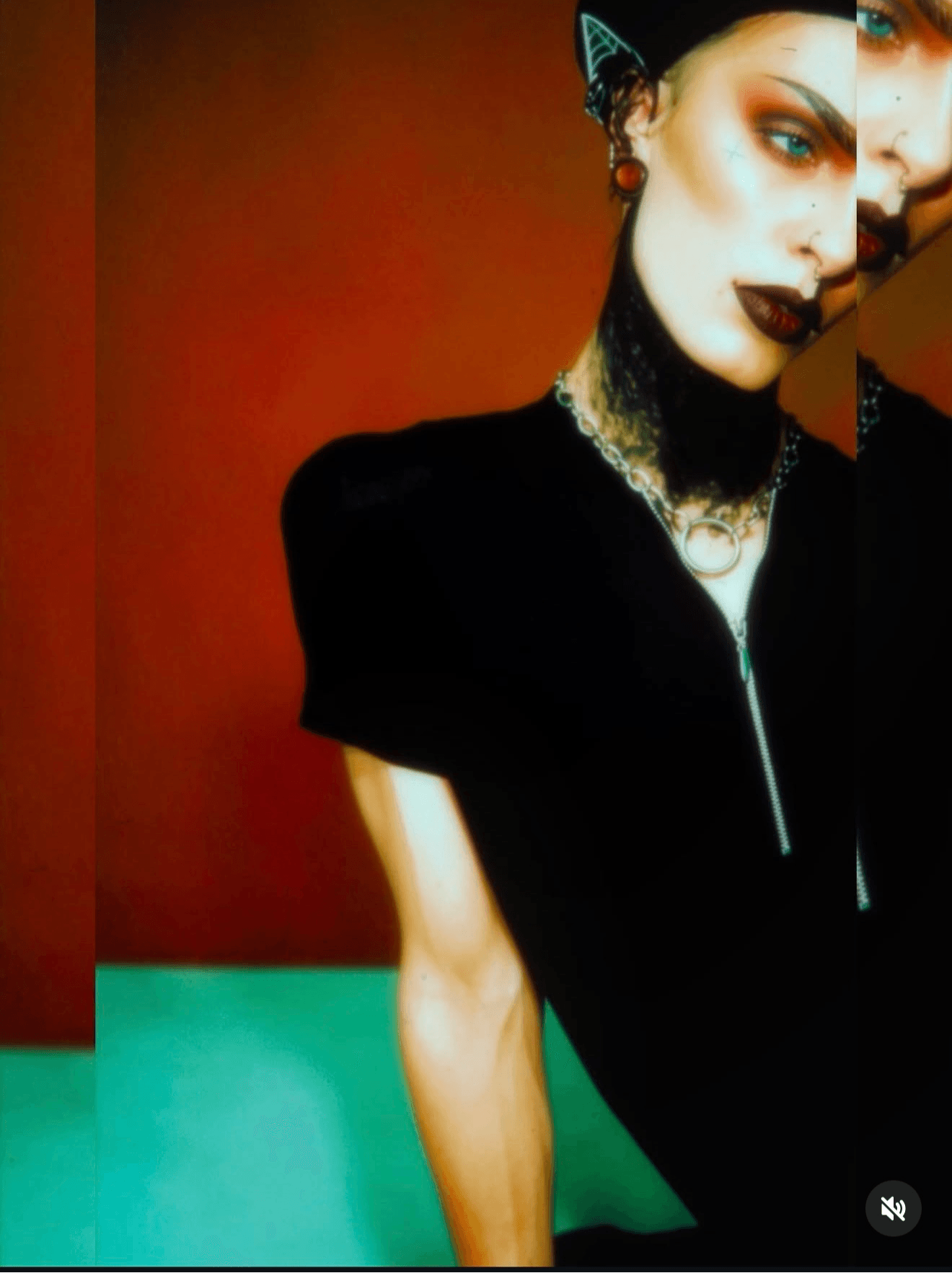 Partially visible woman with dark makeup, jewelry, and a black top against a red background.