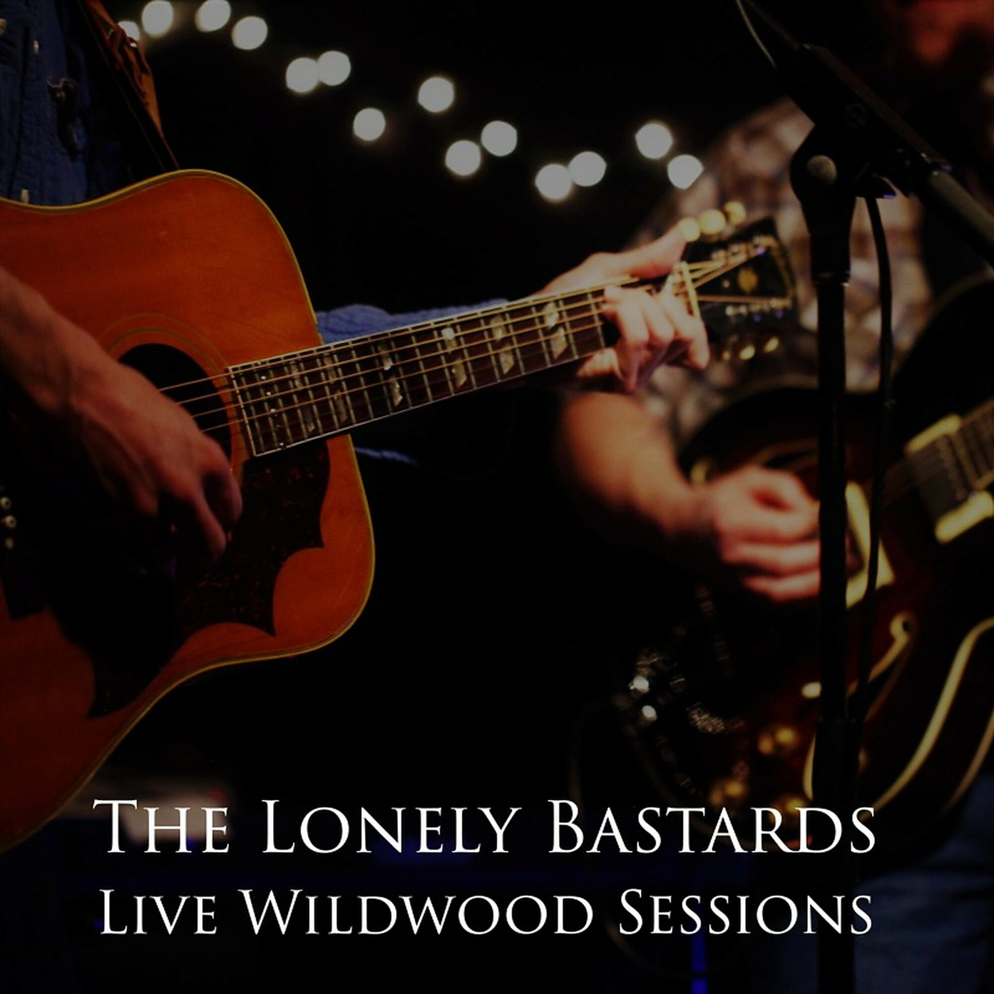 Musicians playing guitars during a live performance with string lights in the background.