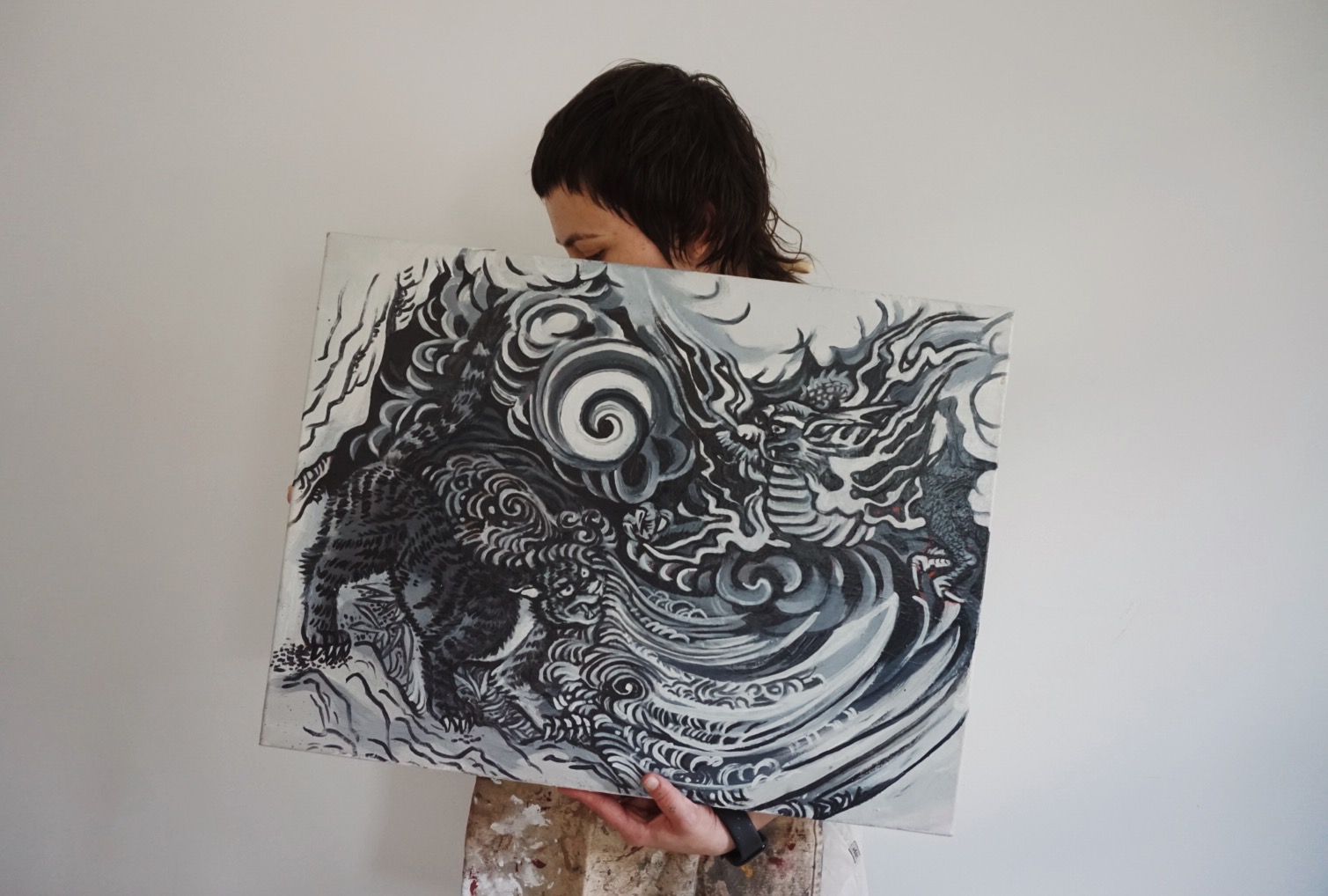 Person holding a black and white abstract artwork with swirling patterns and intricate details, partially covering their face.