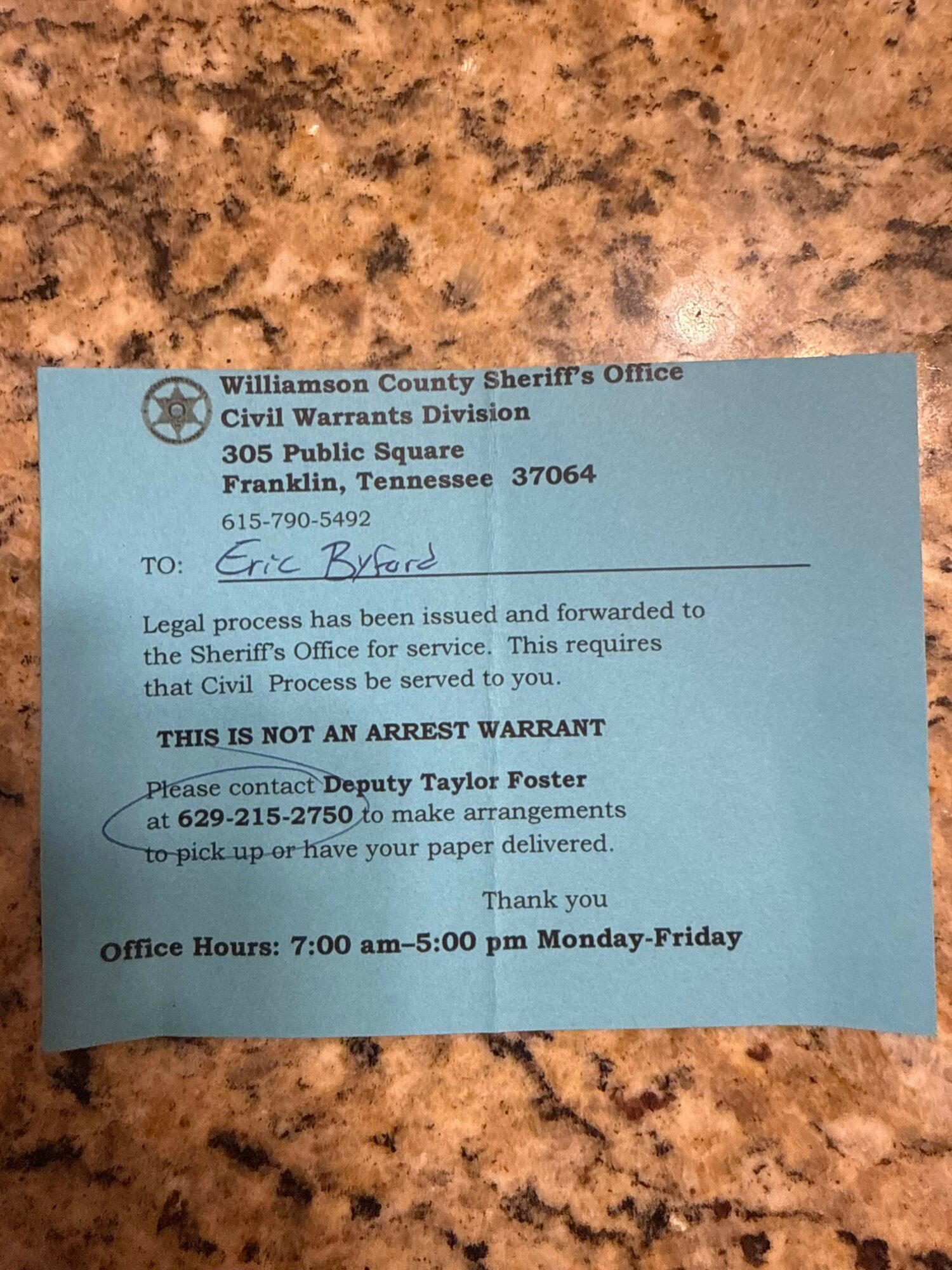 Blue ticket with event details, including date, time, and location, placed on a brown textured surface.