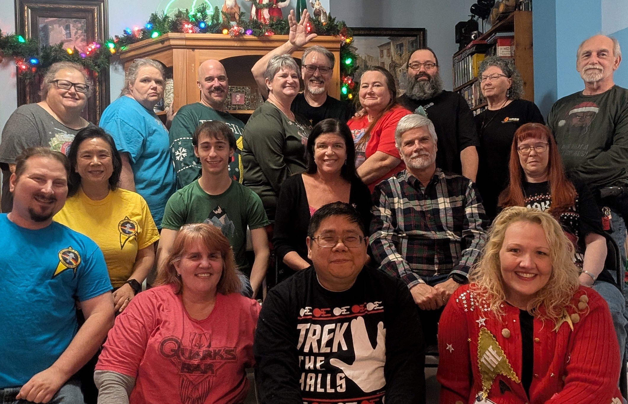 Group of people gathered indoors, some smiling, with Christmas decorations in the background.