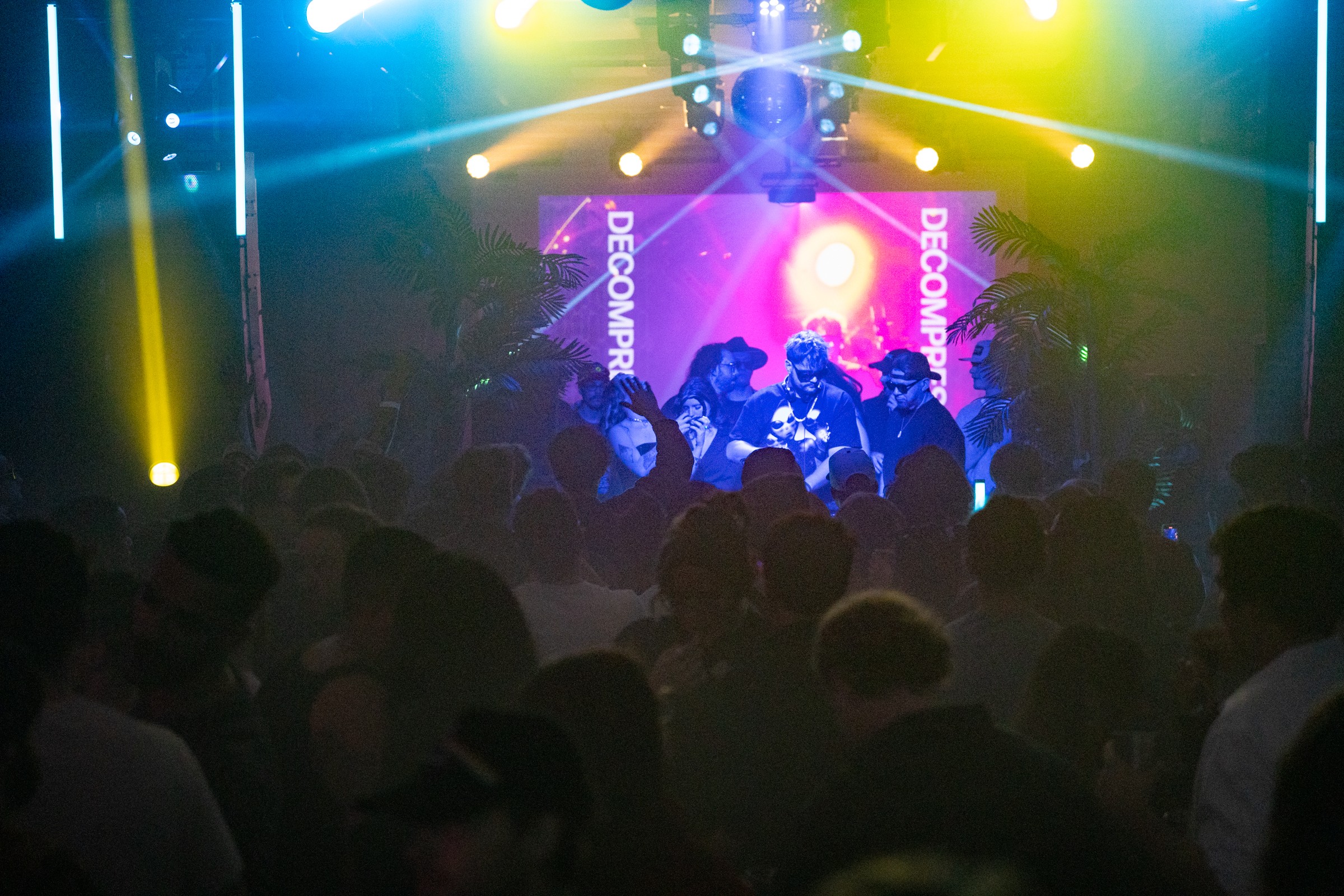 Crowd watching a stage with colorful lights and performers, with a bright central light and banners reading 'BEYOND' in the background.