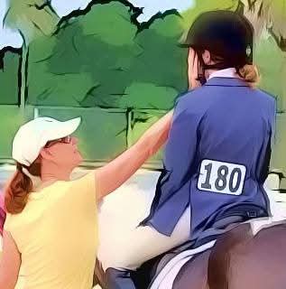 A woman in a yellow shirt and white cap reaches out to a person on horseback wearing a blue jacket with the number 180, outdoors with trees.