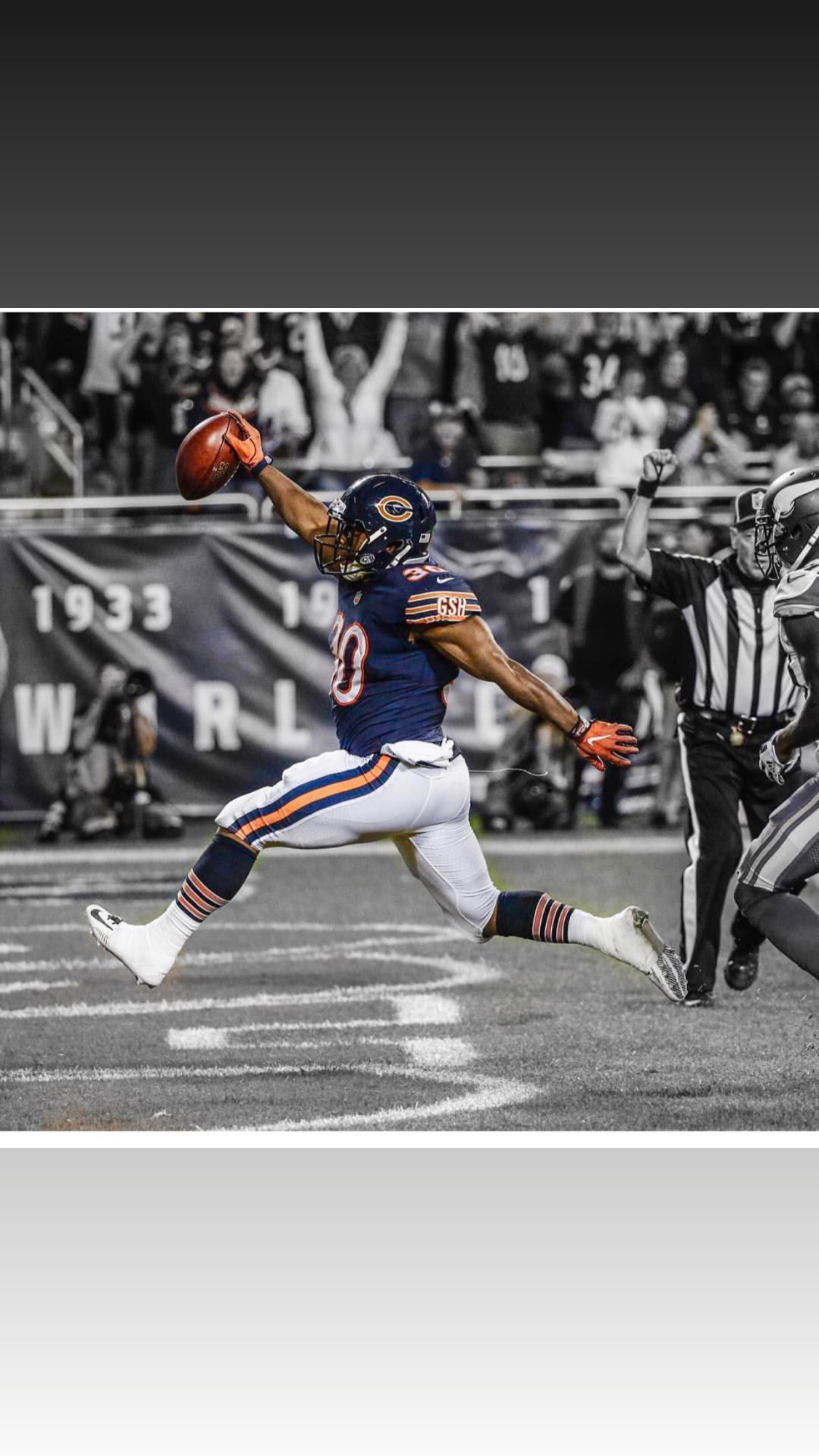 Football player in uniform catches a ball on the field with spectators in the background.